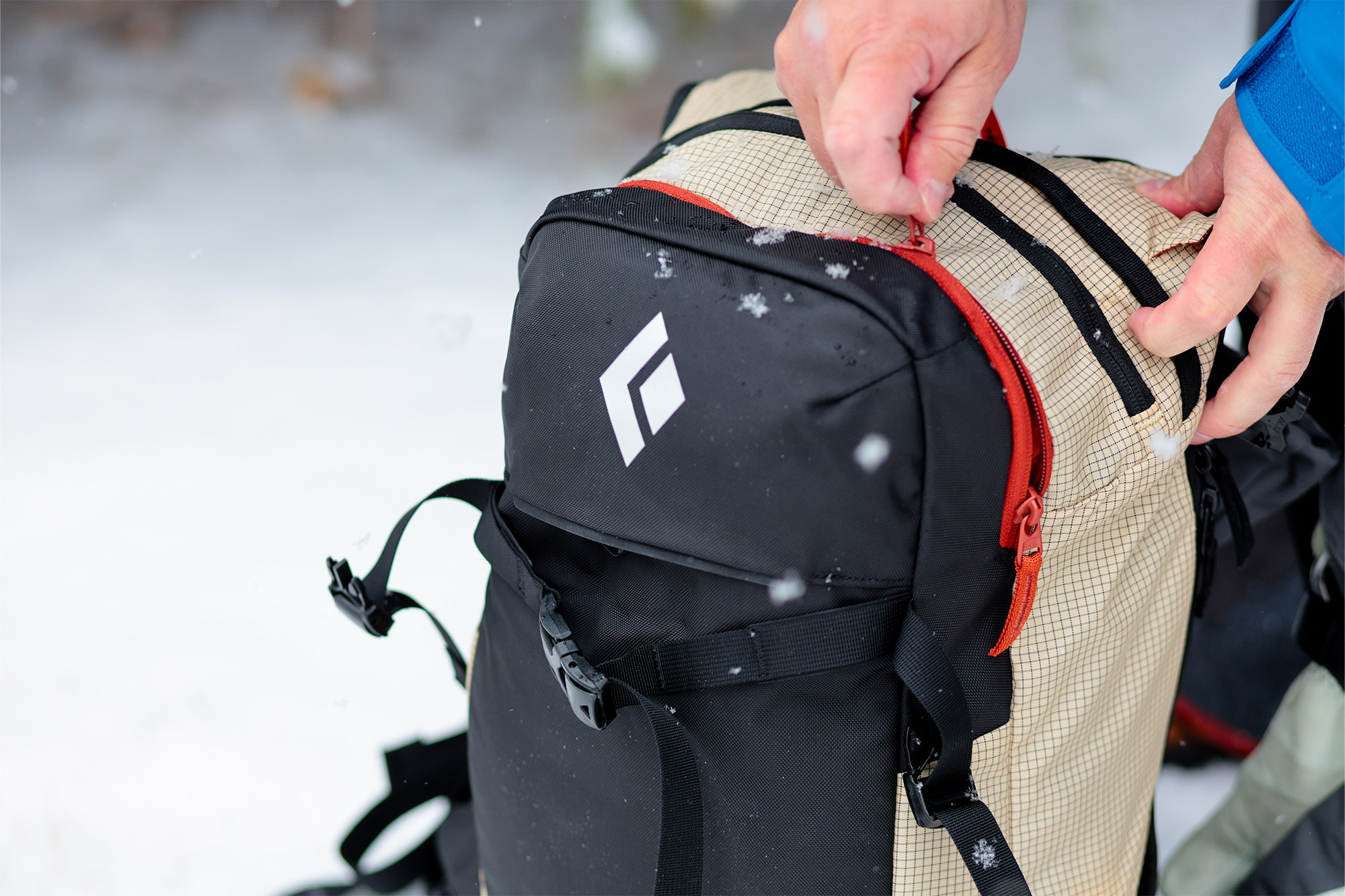 A hand opening the top zippered pocket of the Dawn Patrol pack