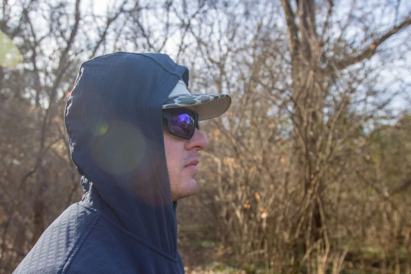 An angler with sunglasses on with the hood of the Free Fly Gridback Fleece Anorak Hoodie pulled up.