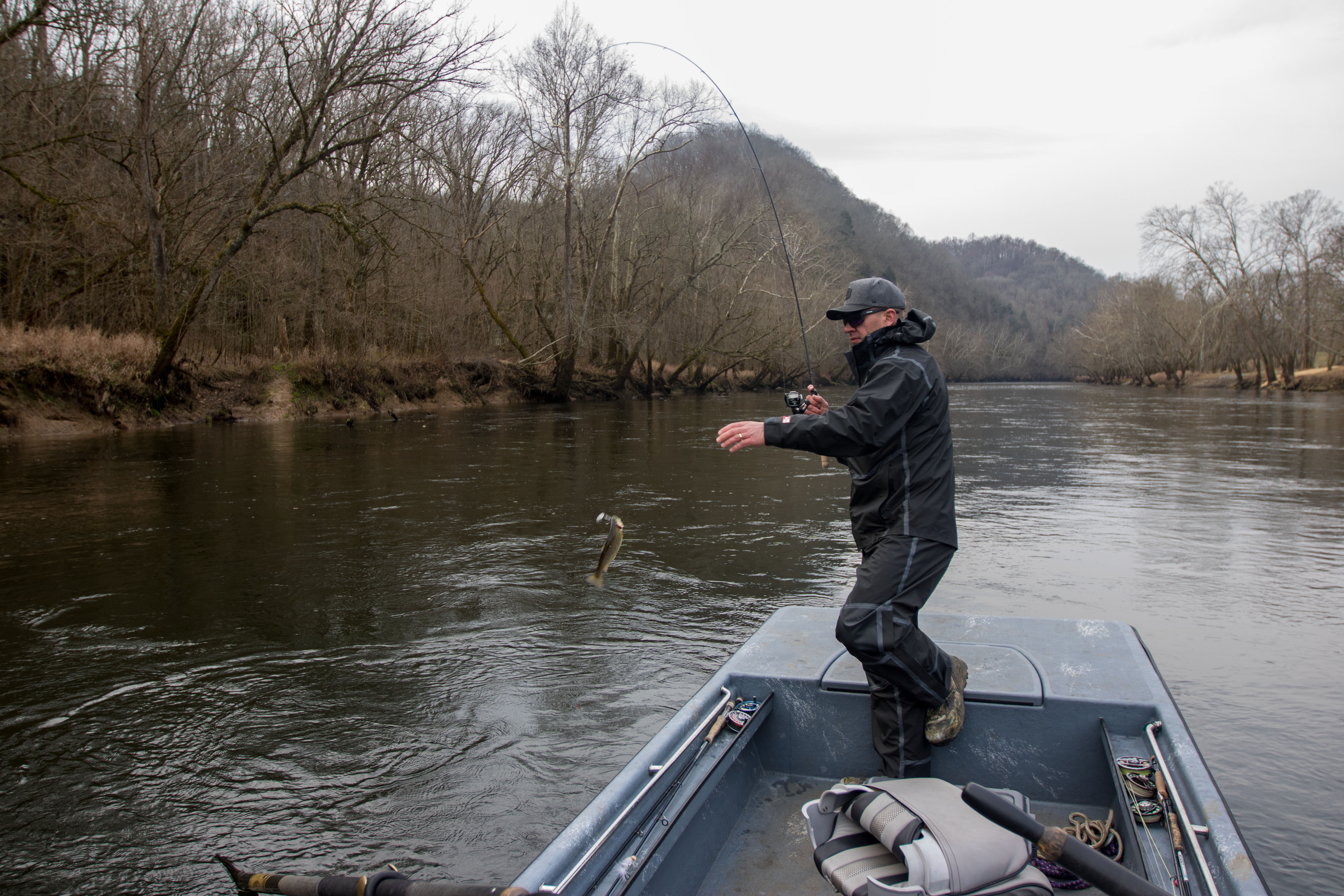 An angler lifting a trout into the boat with the Shimano Compre Light Spinning Rod.