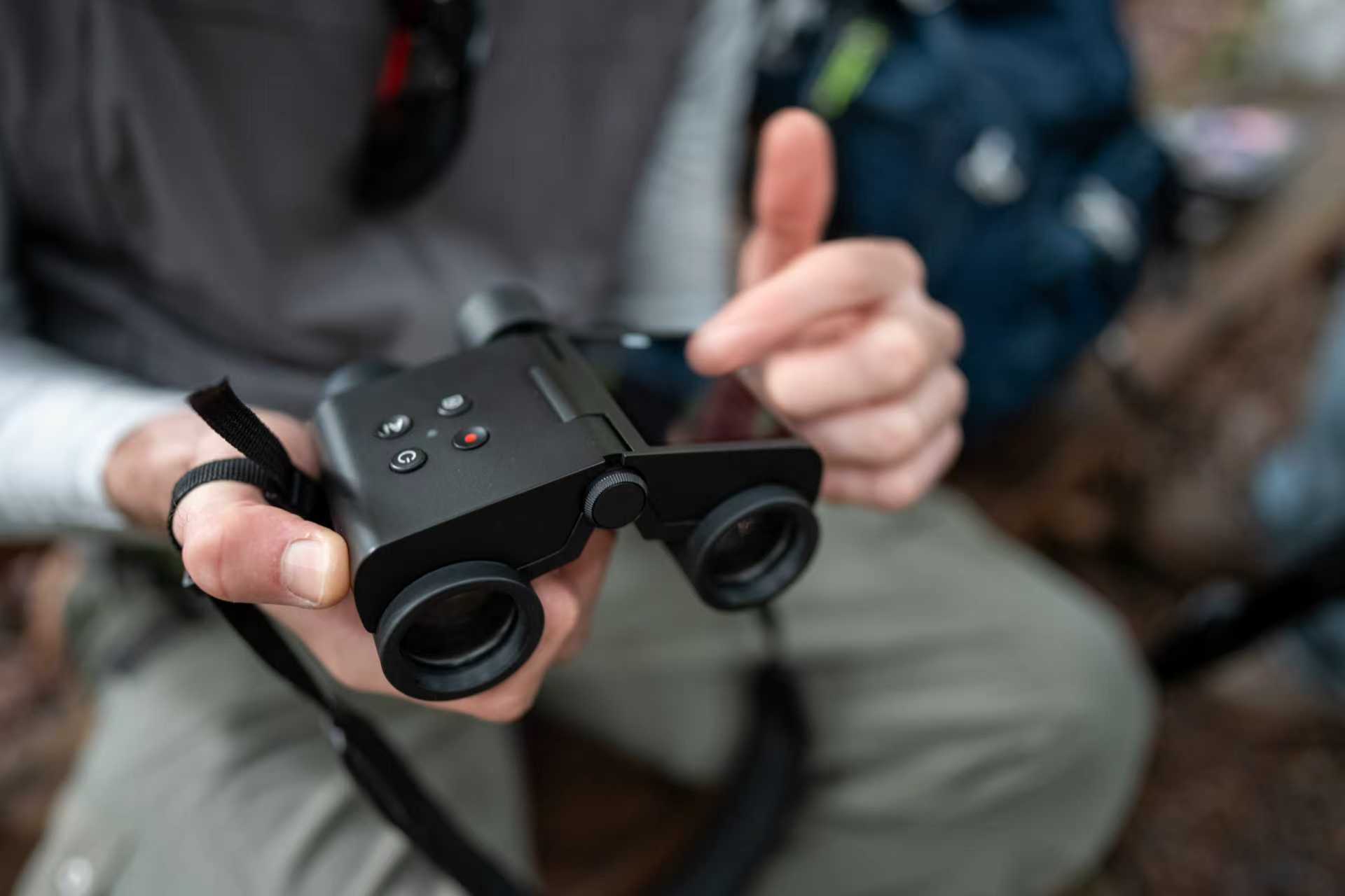Hands holding the MatataXplore Solvia ED 8x32 AI Binoculars, showing the top buttons and eyepieces