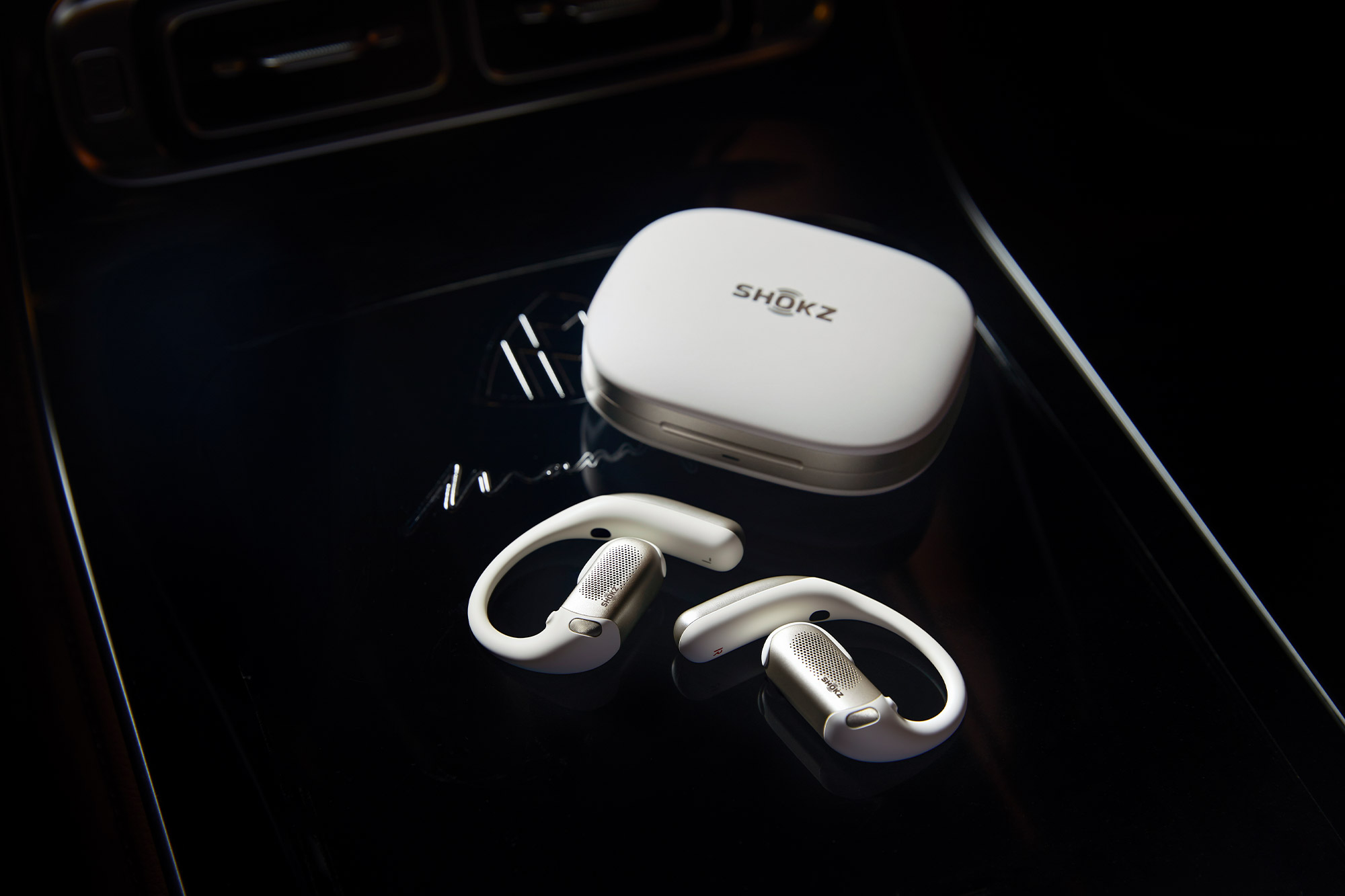 OpenFit Pro earbuds and the charging case are placed on a dark glass surface