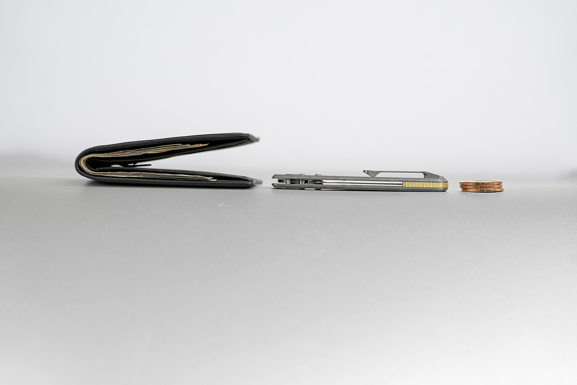 Racoon TiSlim knife placed next to a wallet and coins to show slim carry profile