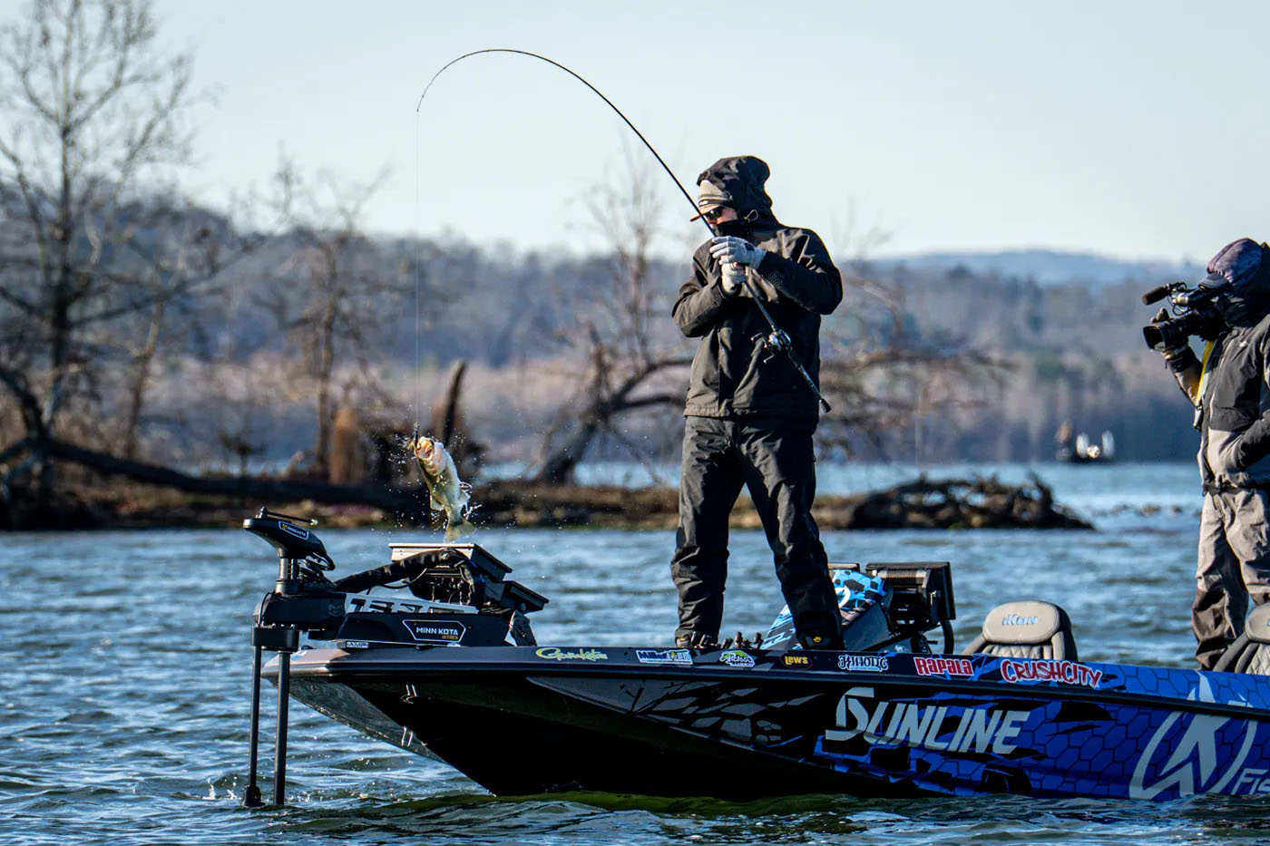 An angler lifting a bass on his boat at the Bassmaster Elite Series on Lake Guntersville.