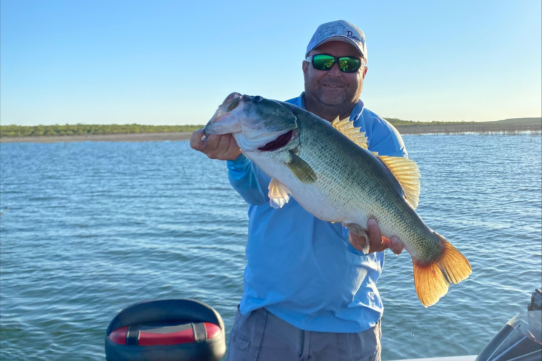 World Bass Enterprises Founder and CEO Brian Bird holding a large bass on a lake.