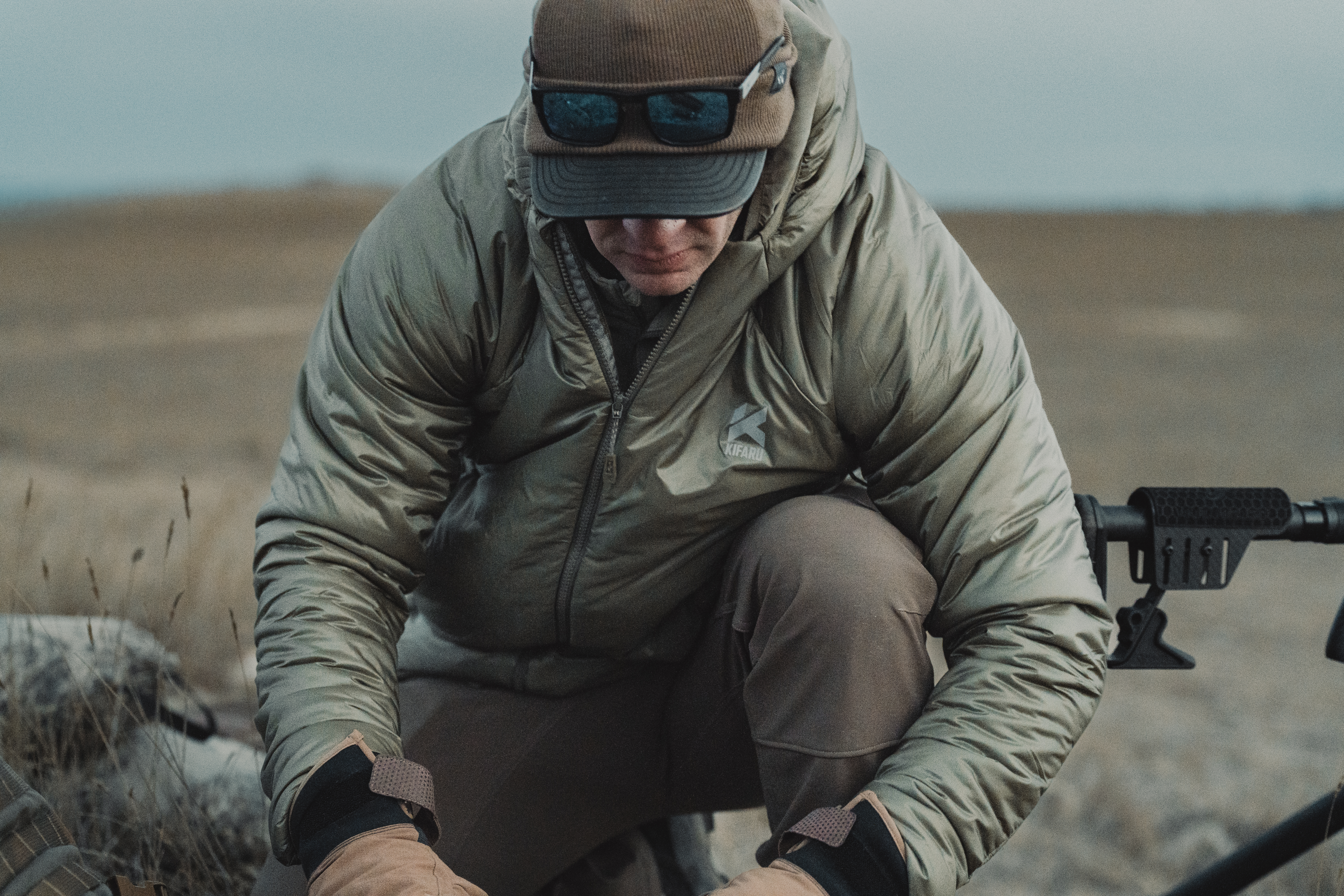 A hunter crouched over digging through a pack.