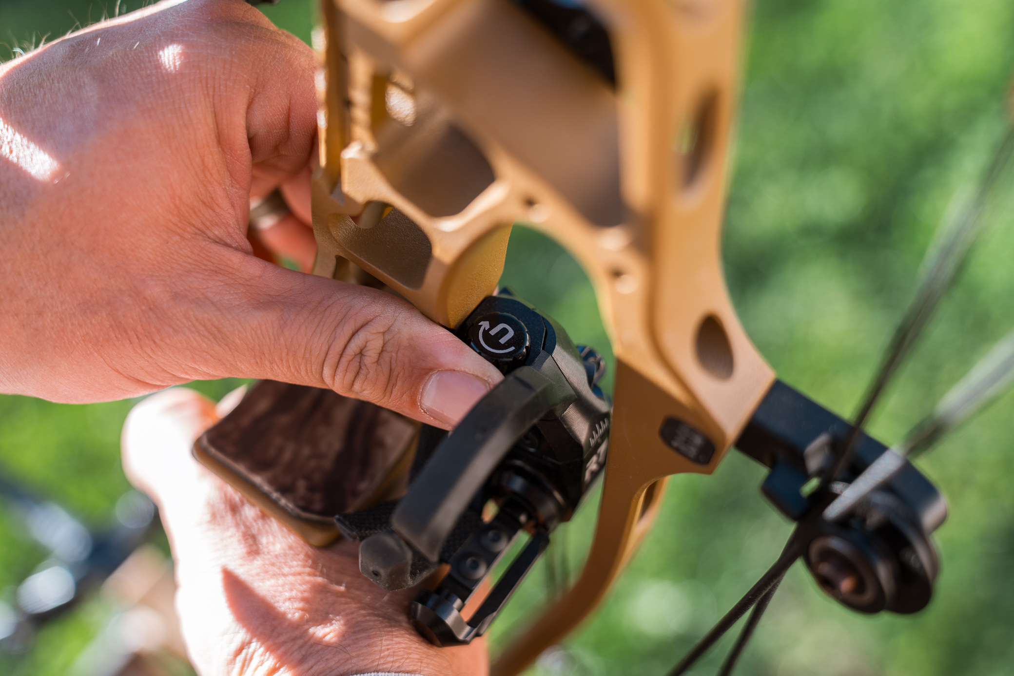 A hand adjusts the controls on the arrow rest mounted to a compound bow
