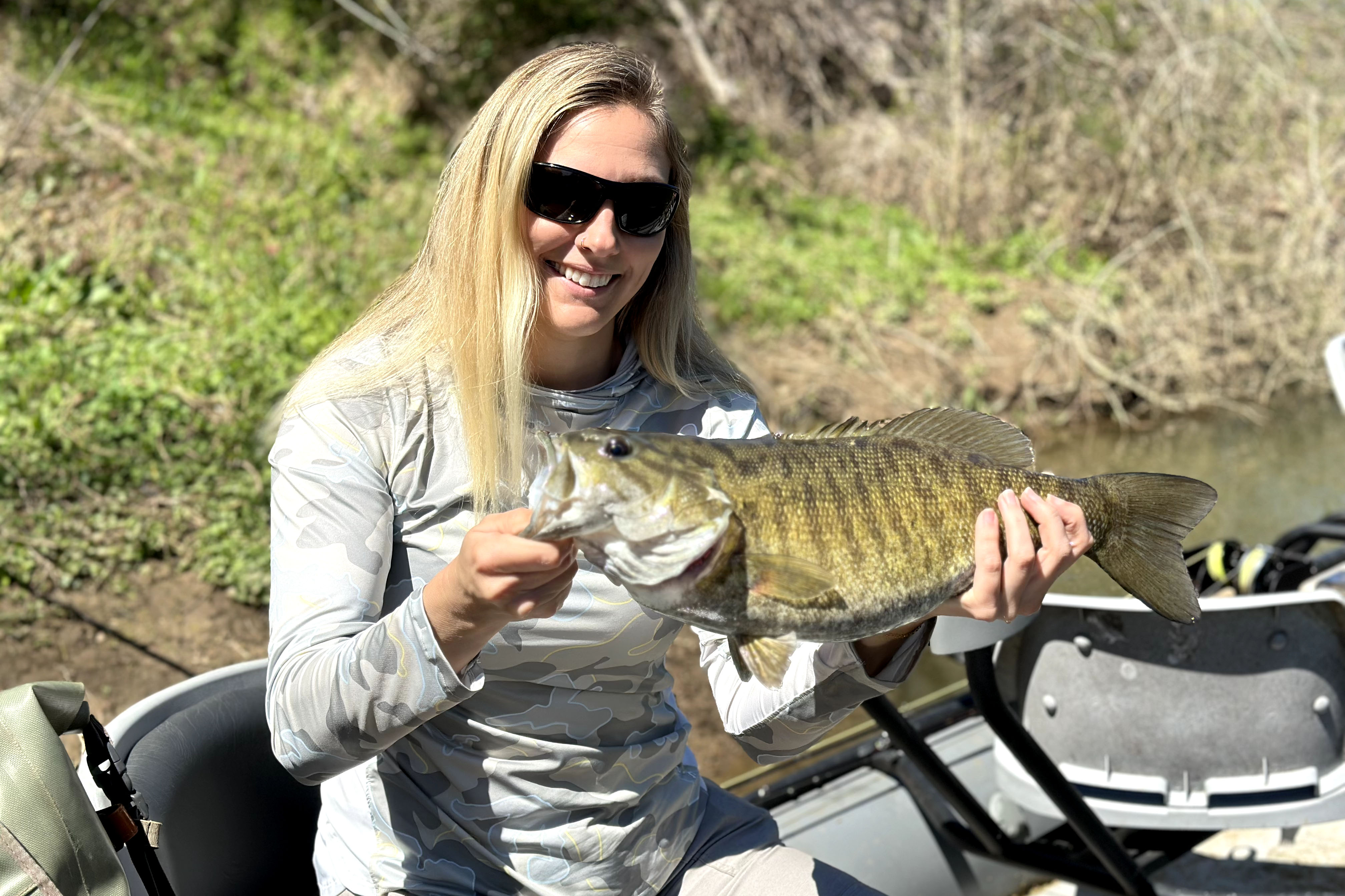 A woman holding a smallmouth bass.
