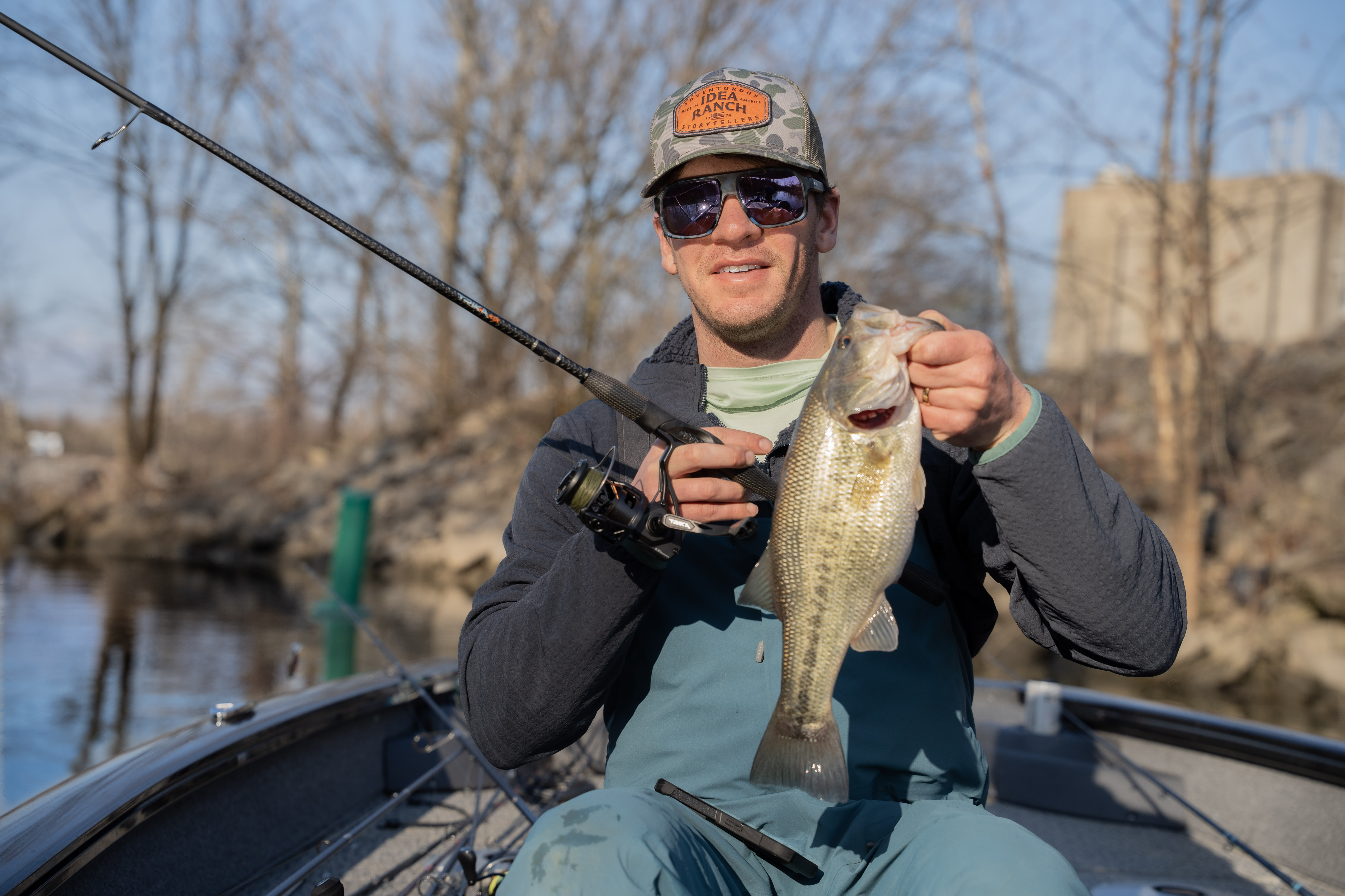 An angler holding a bass caught on the Trika 10X rod