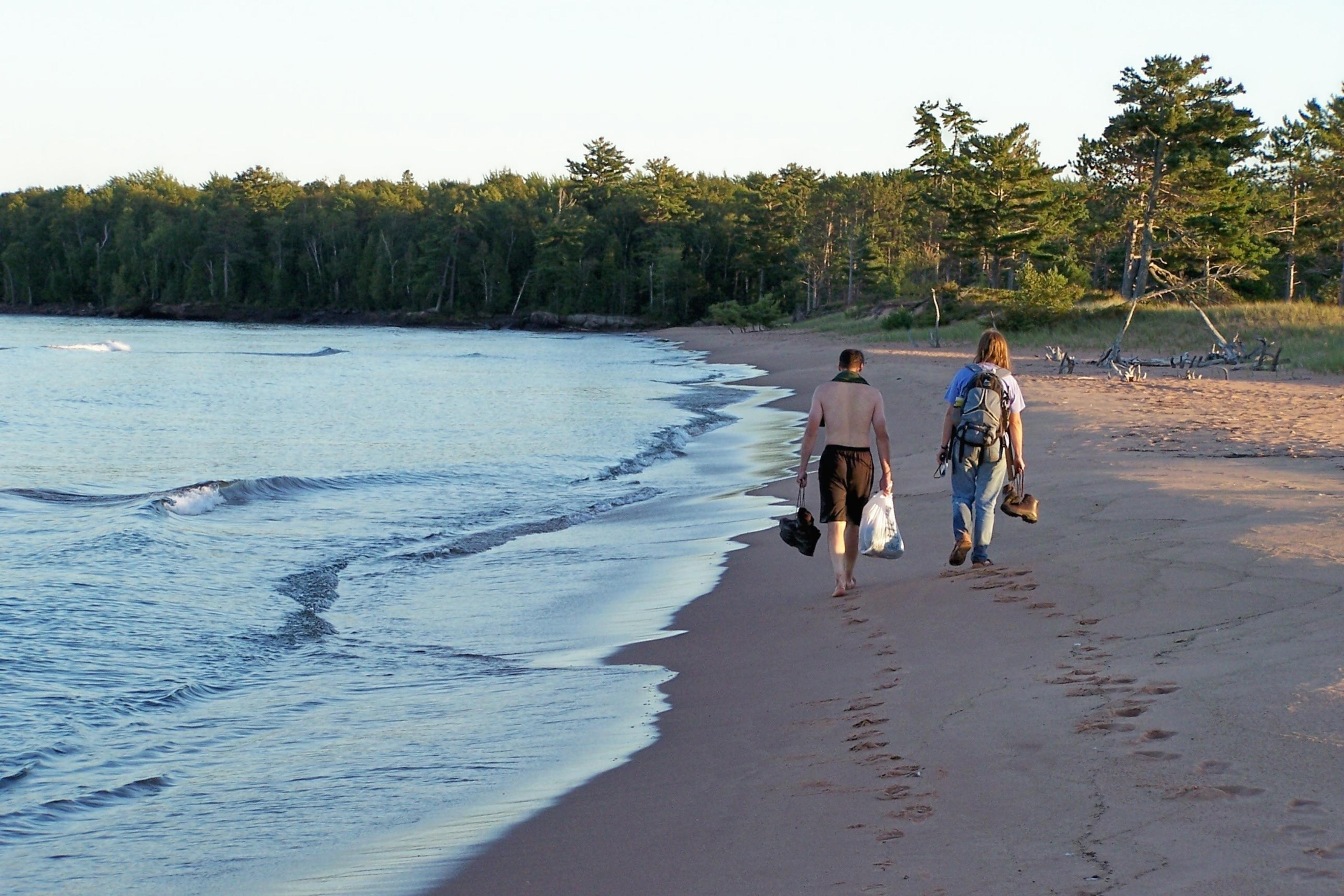 two people walk along beach