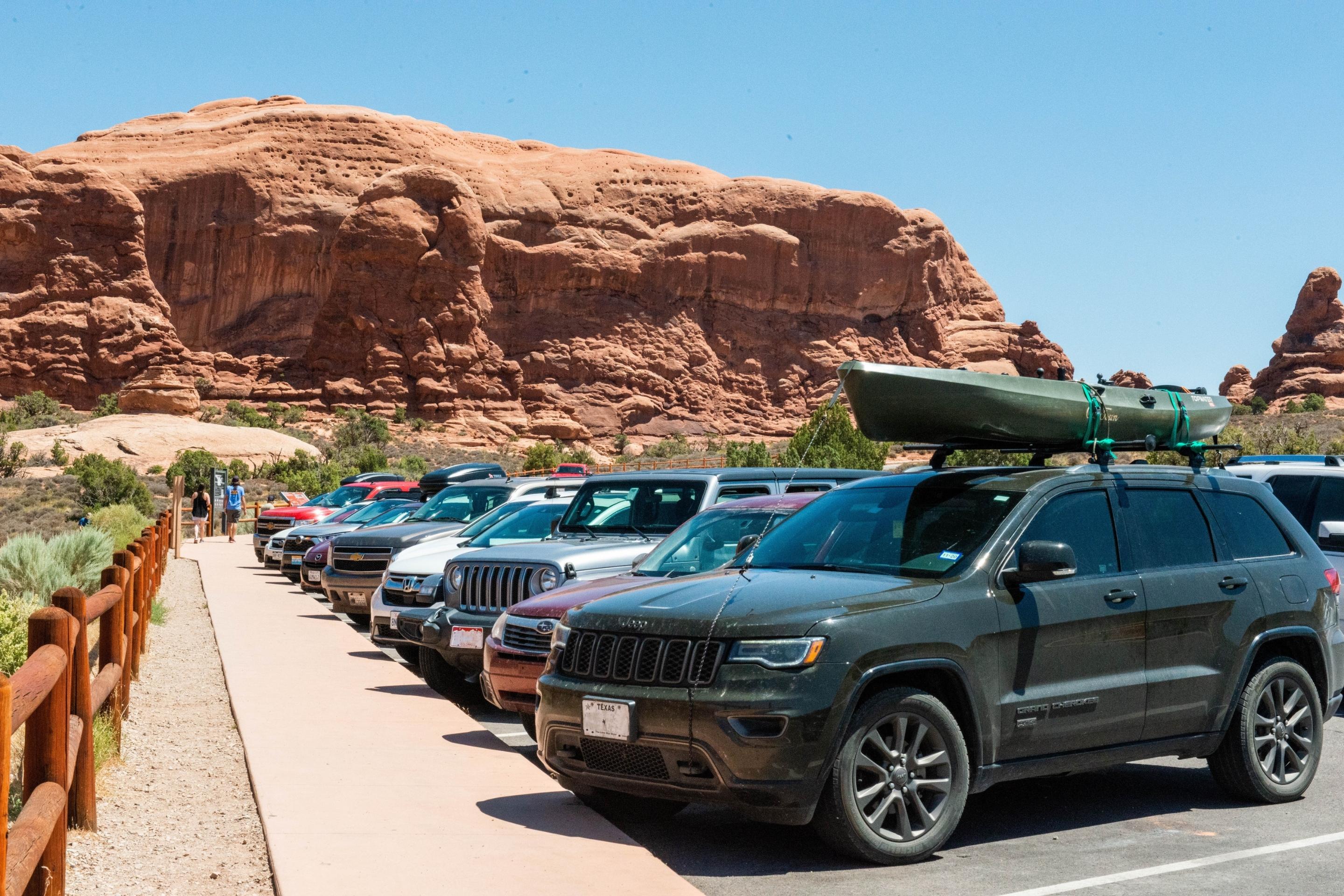 parking lot full of cars, red rocks in background