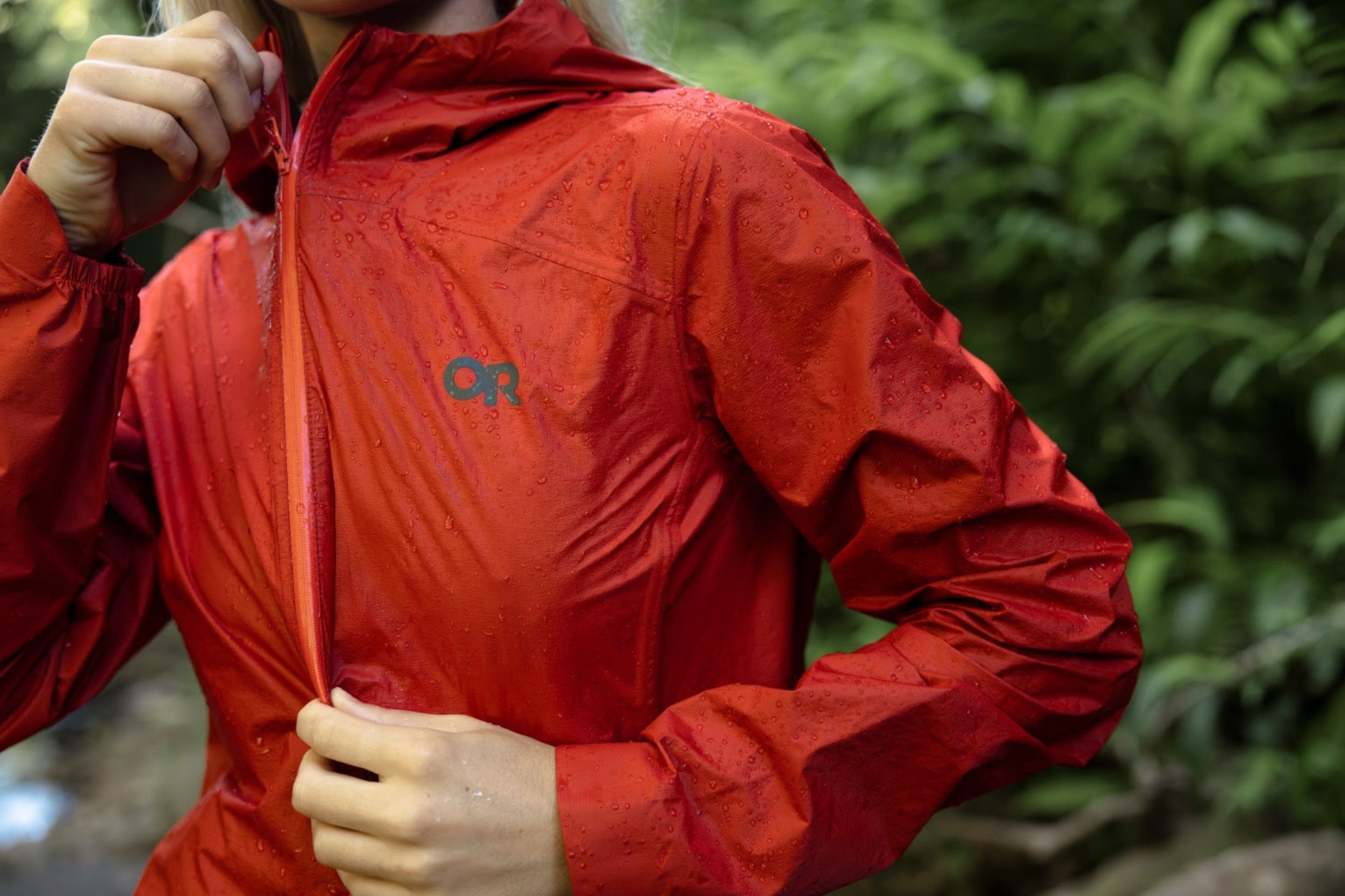 close up shot of person zipping up red jain jacket in the rain