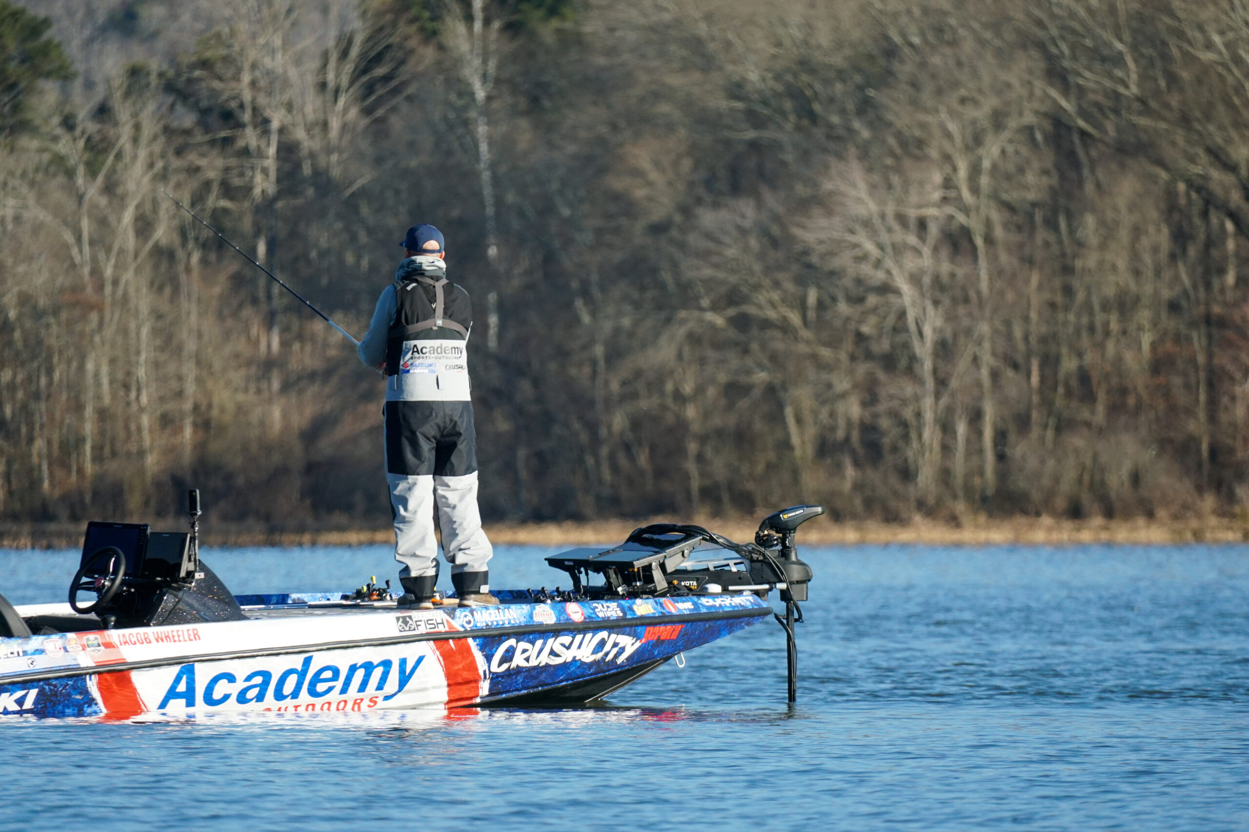 A bass angler on the bow of a boat, fishing.