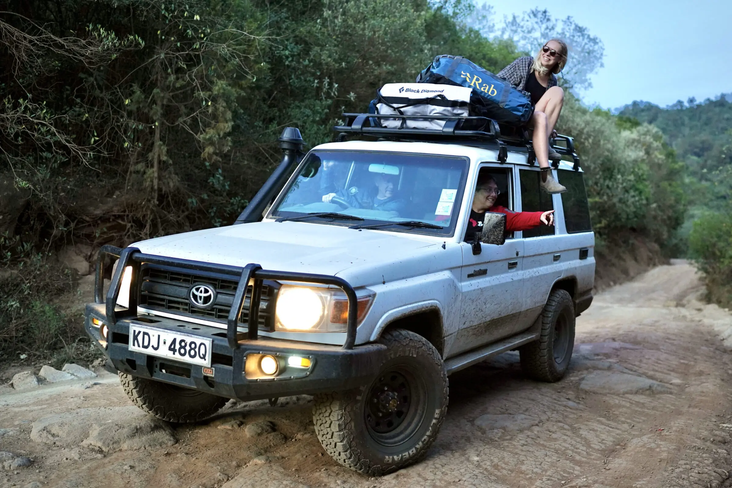 Girl on top of truck with duffel bags