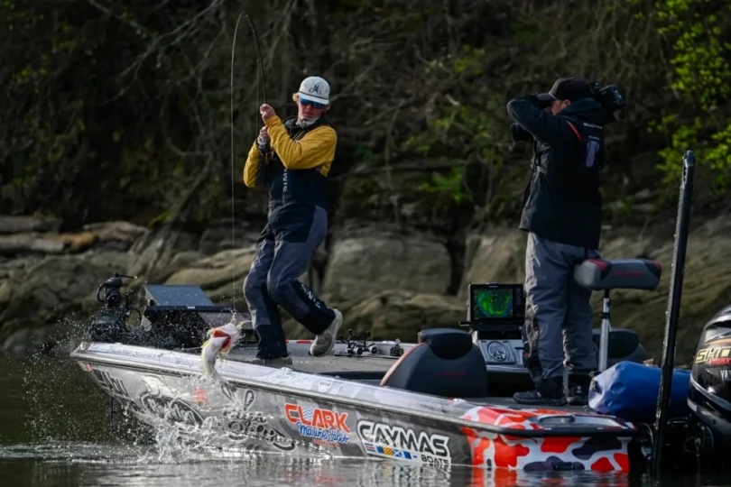 An angler lifting a bass into a boat.