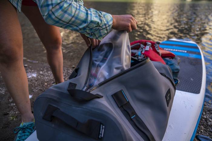 woman loading a small dry bag into a larger dry bag duffle 