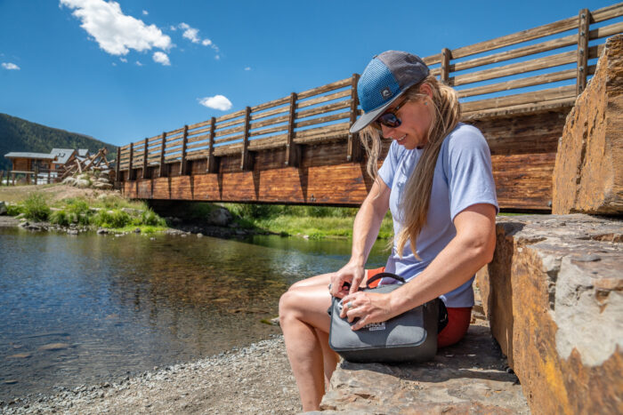 clipping soft cooler next to river 