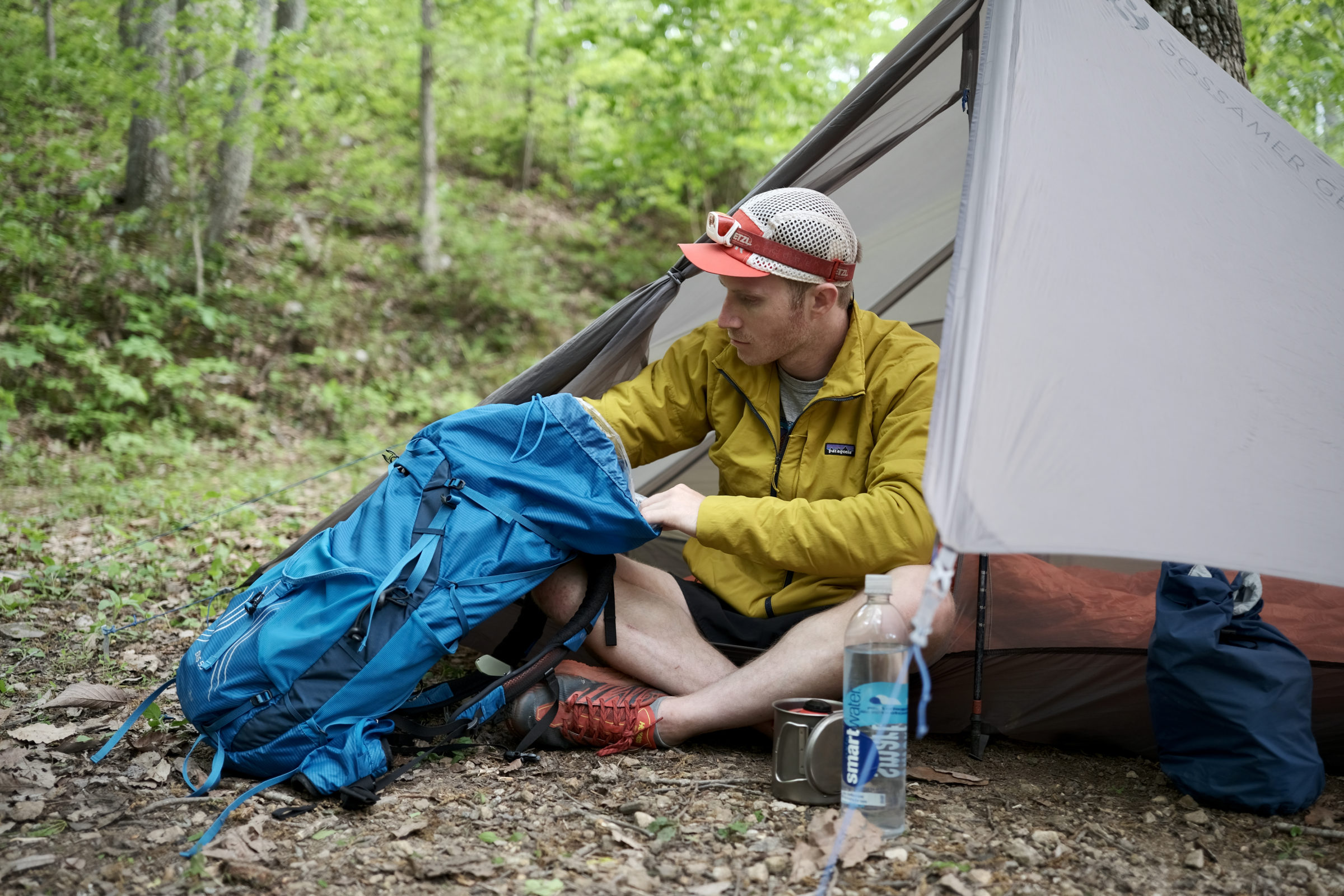 a backpacker looks through the osprey exos 58 pack outside his tent