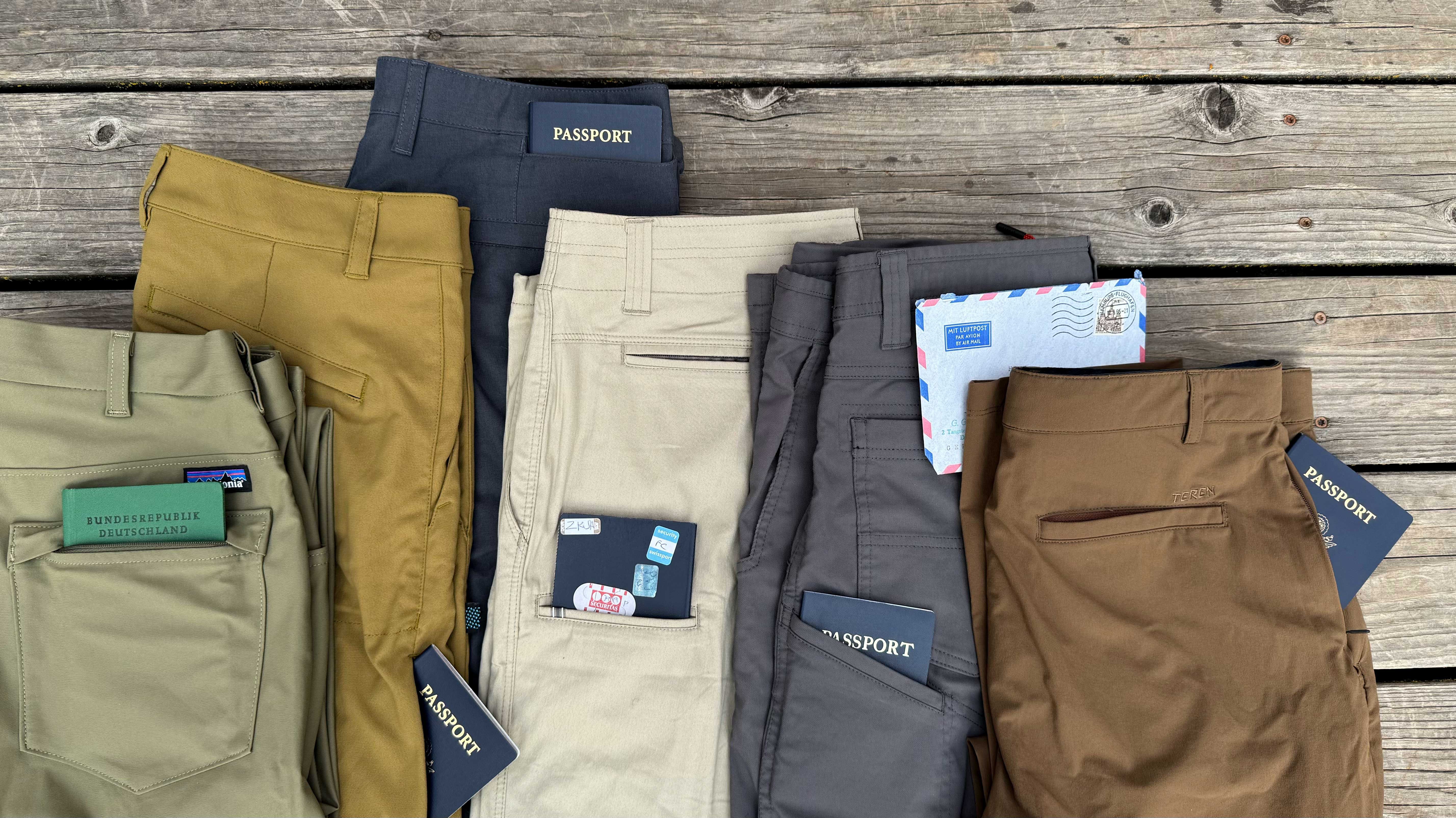 a selection of travel pants laid on a wooden deck