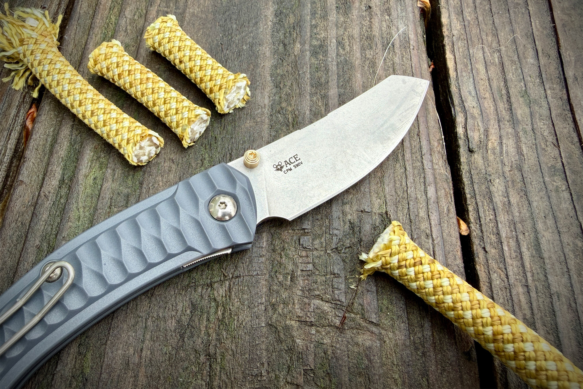 The GiantMouse ACE Iona Sailor folding knife resting on a wooden surface next to cut rope pieces