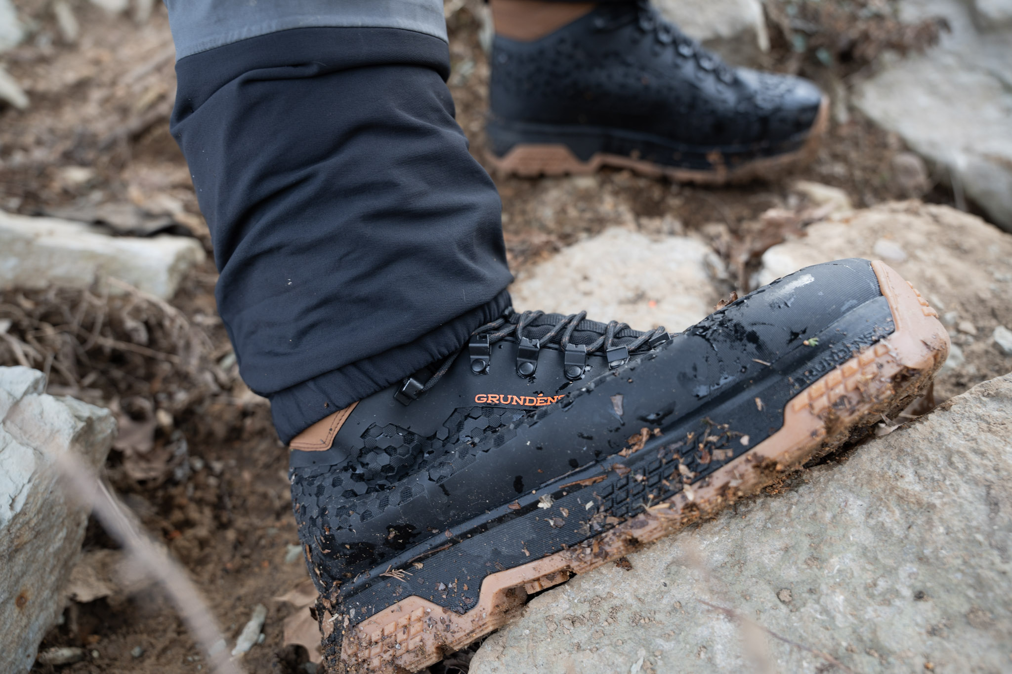 The Grundéns Rock Armor wading boots bending as an angler climbs on rock.
