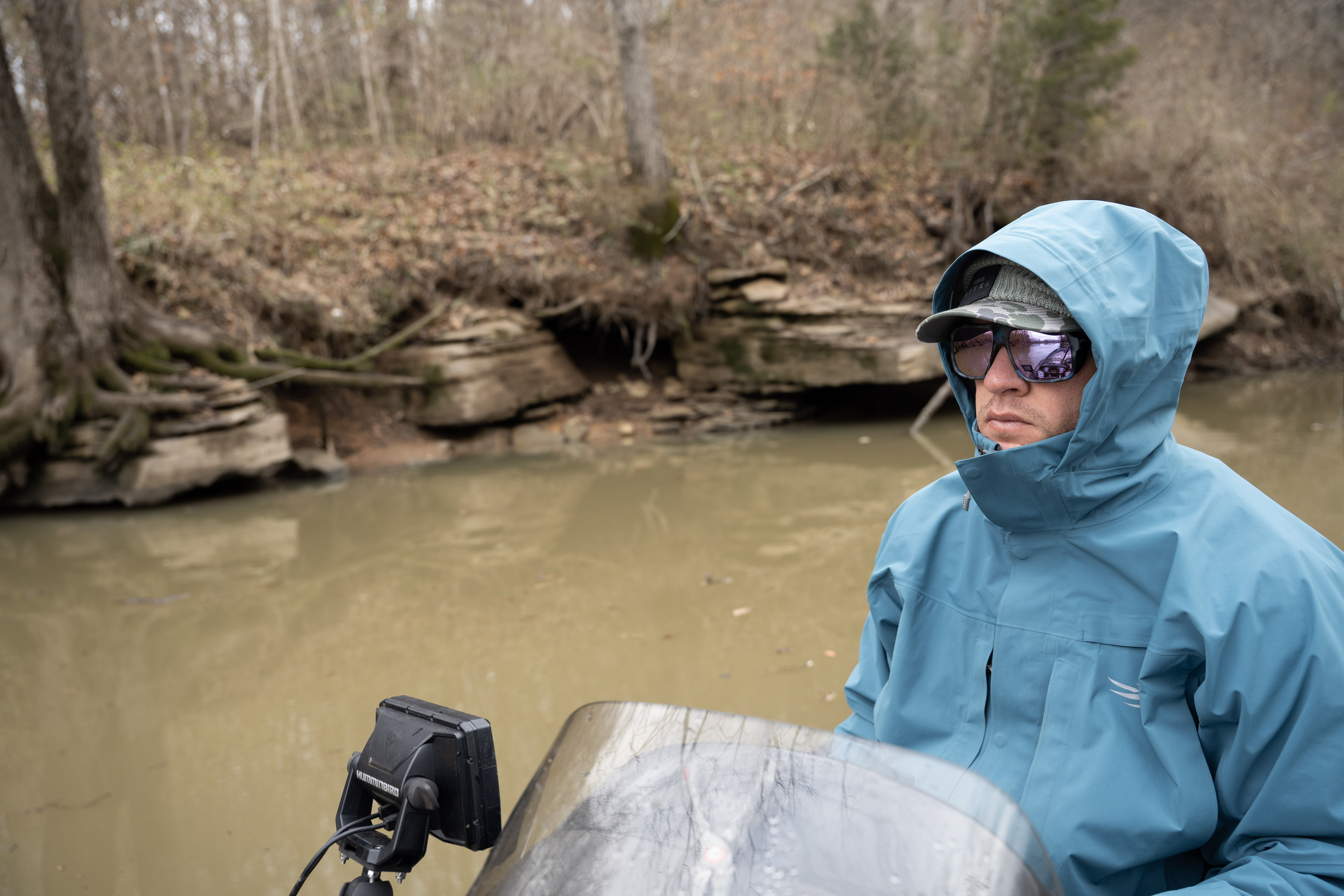 A man driving a boat with the SITKA Cat 5 jacket on.