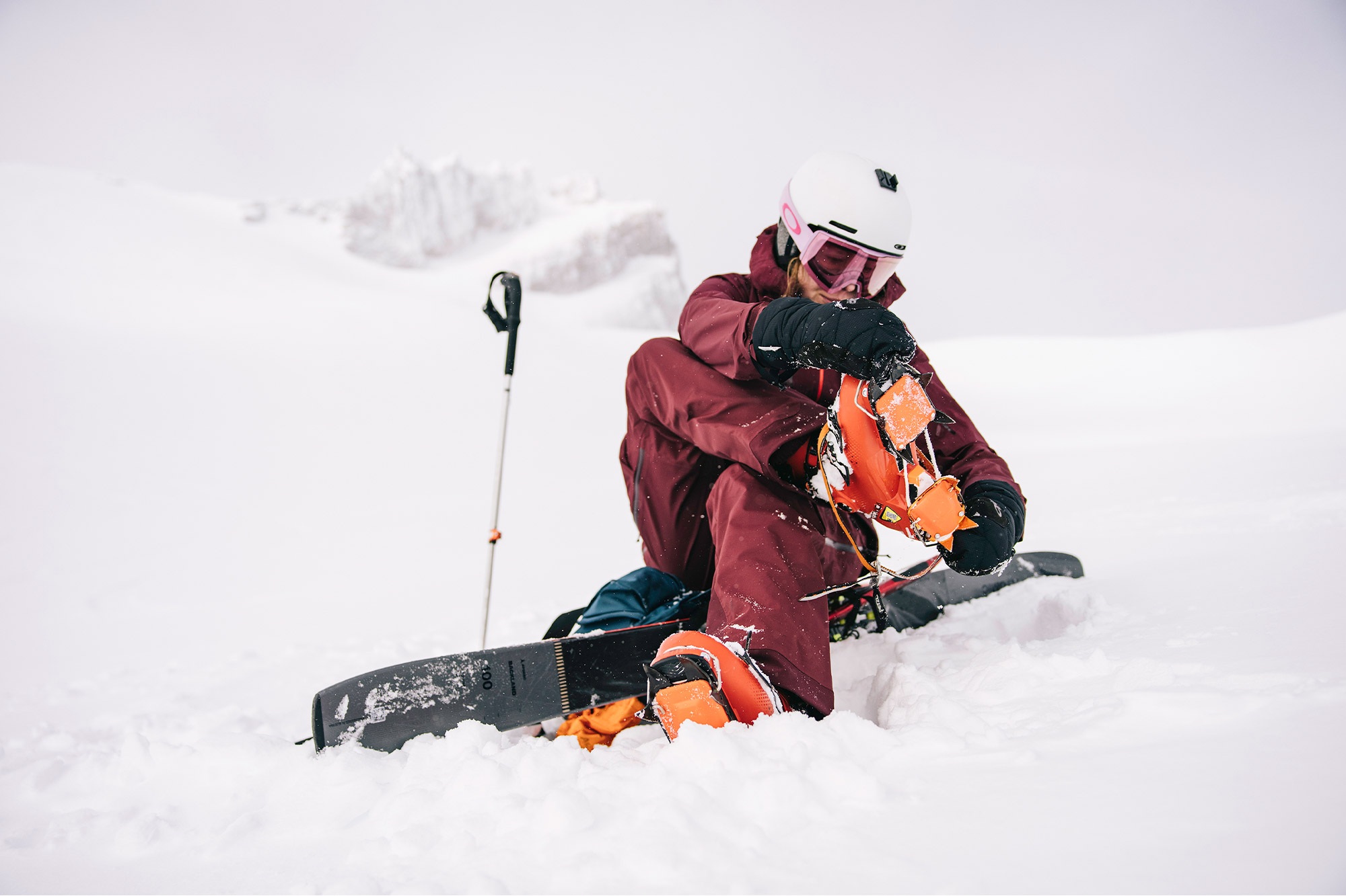 Backcountry skier putting on crampons during spring ski tour