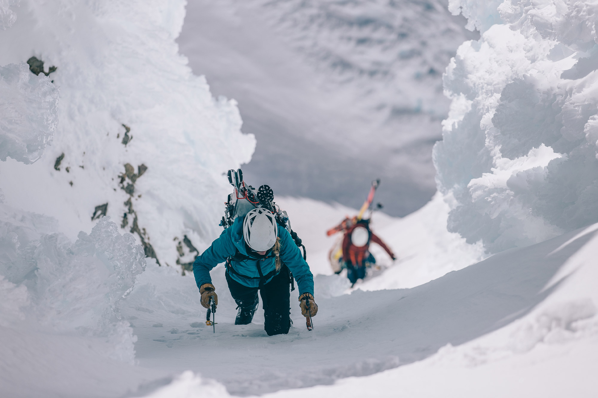 Ski mountaineers ascending steep couloir using ice axes