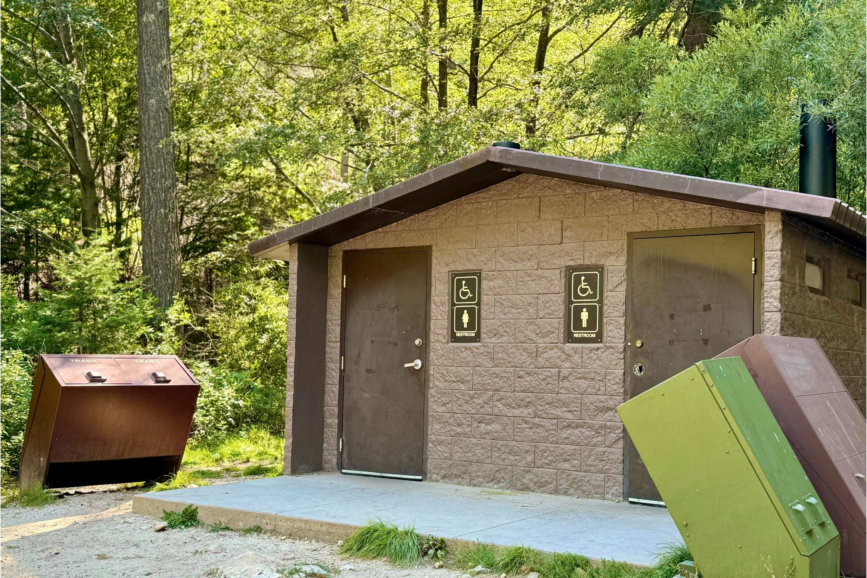 trail bathroom in the woods with garbage cans