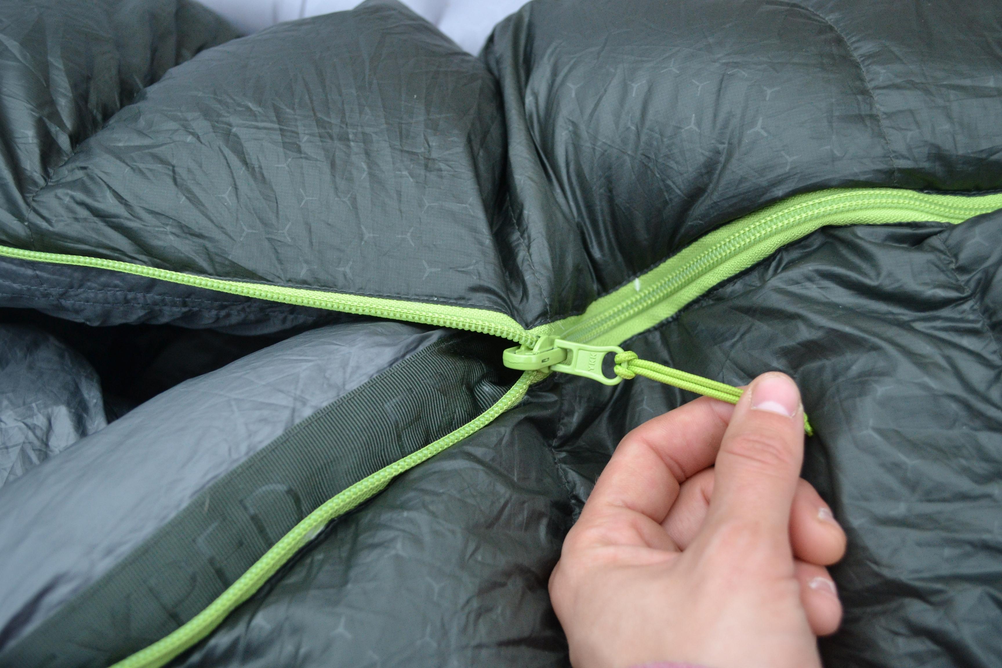 close-up shot of person pulling a zipper on a sleeping bag
