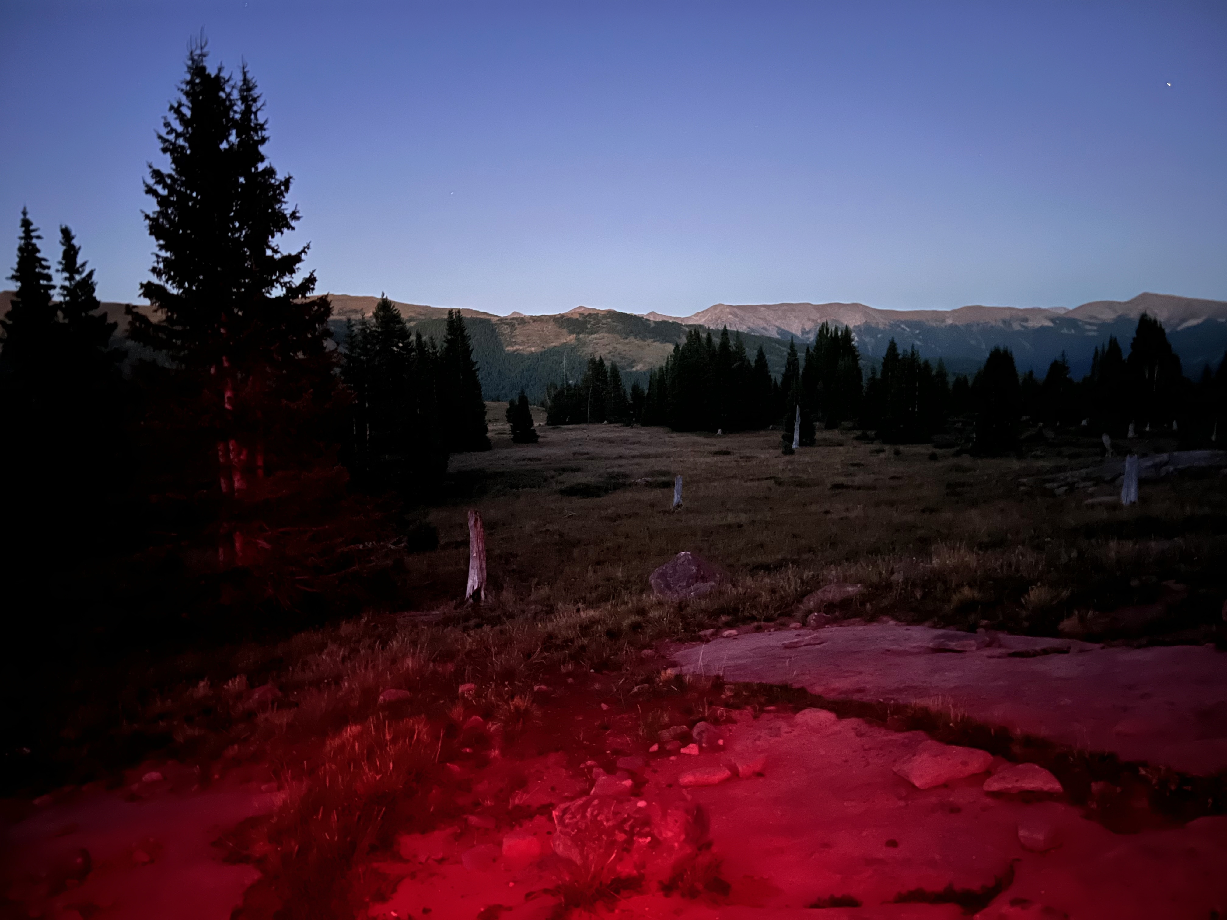Red light of headlamp in mountains at dusk