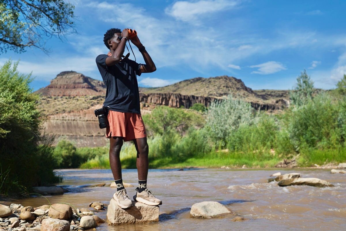 A man looks through binoculars while wearing hiking boots