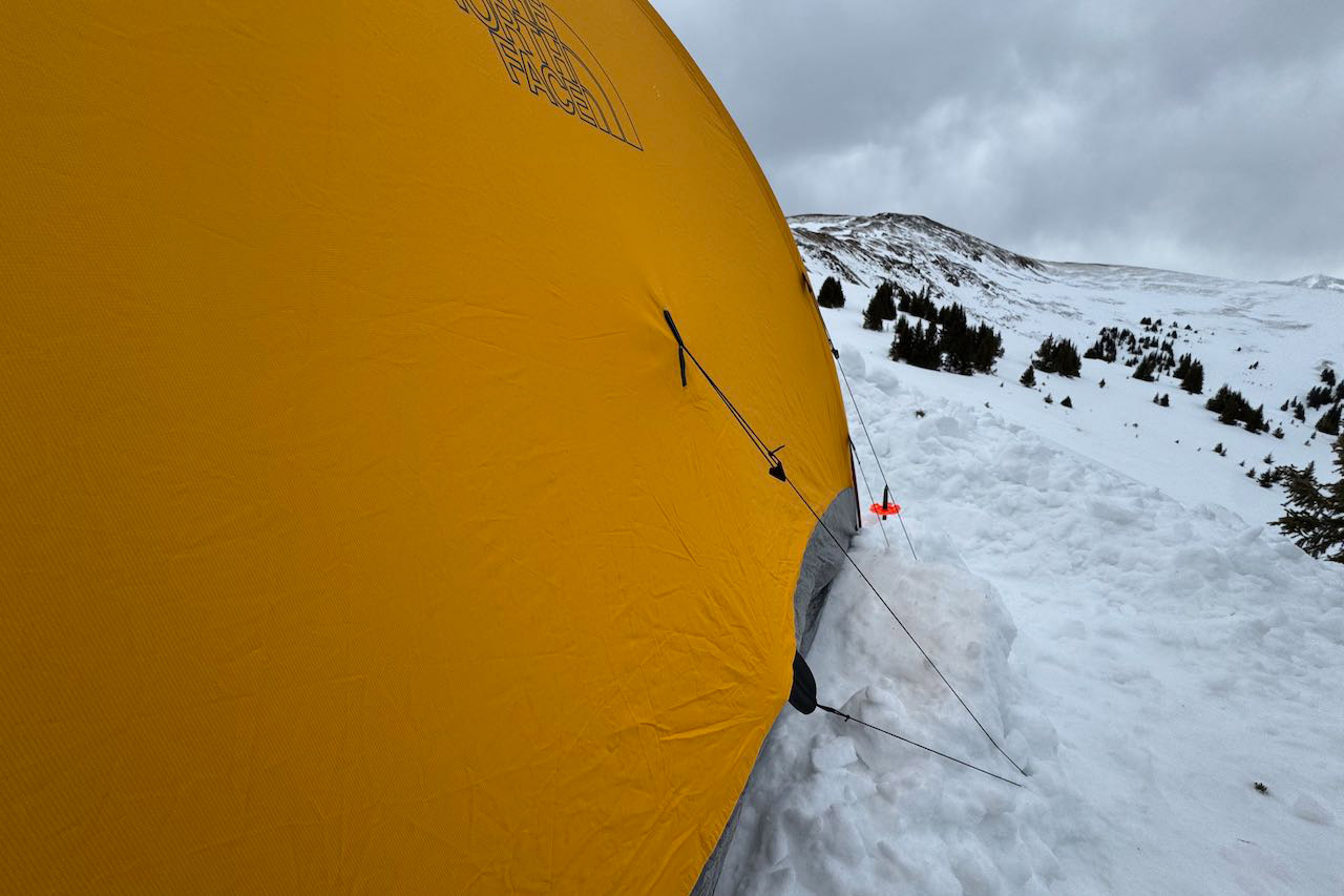 Yellow Assault 2 tent wall with guyline secured in snow