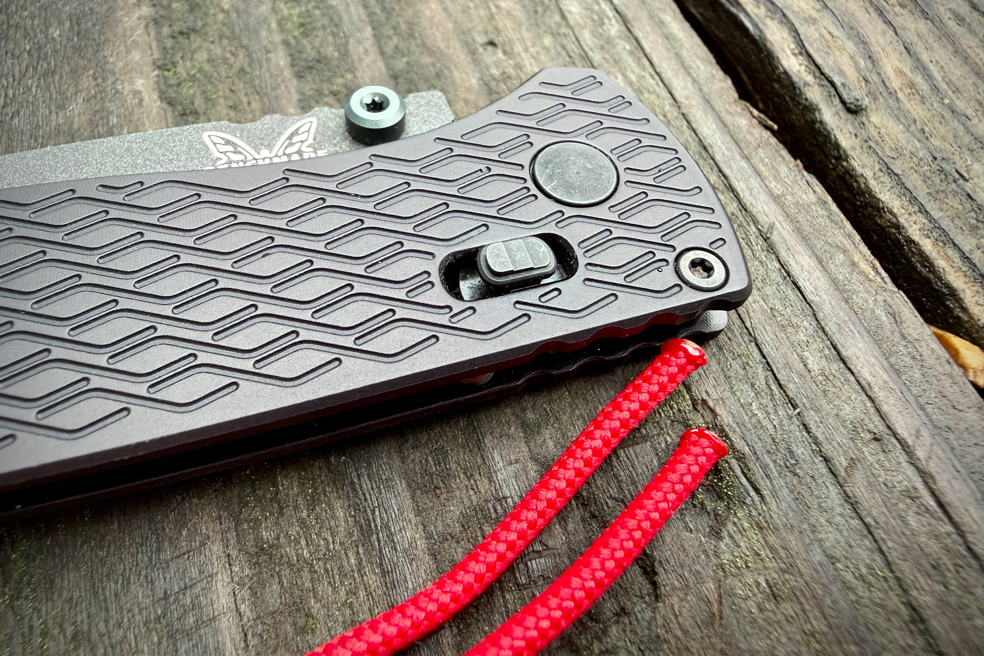 Benchmade Bugout Vapyr handle texture and AXIS lock detail with red lanyard on wood