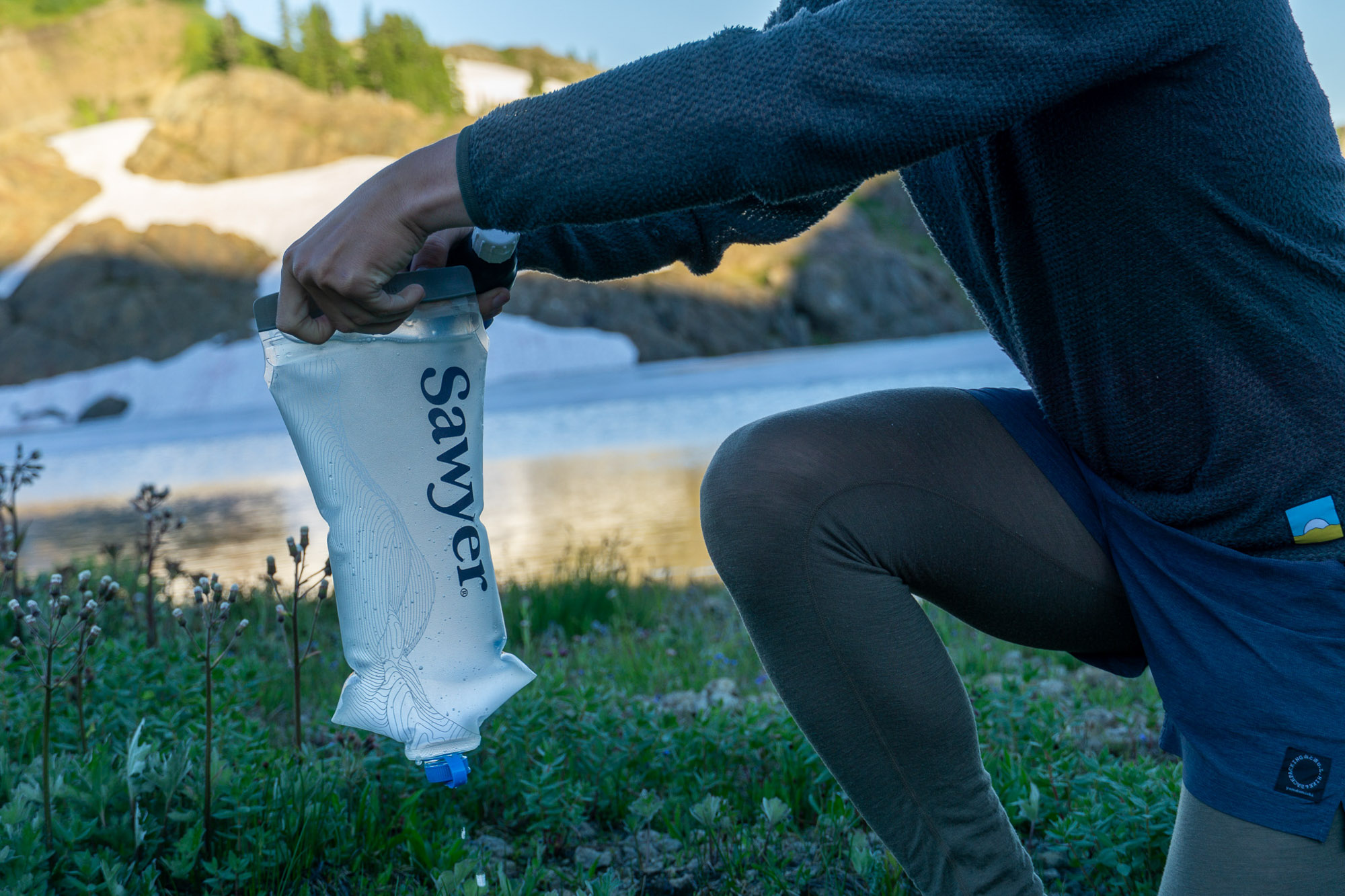 the author filters water with the sawyer squeeze beside an alpine lake in washington state