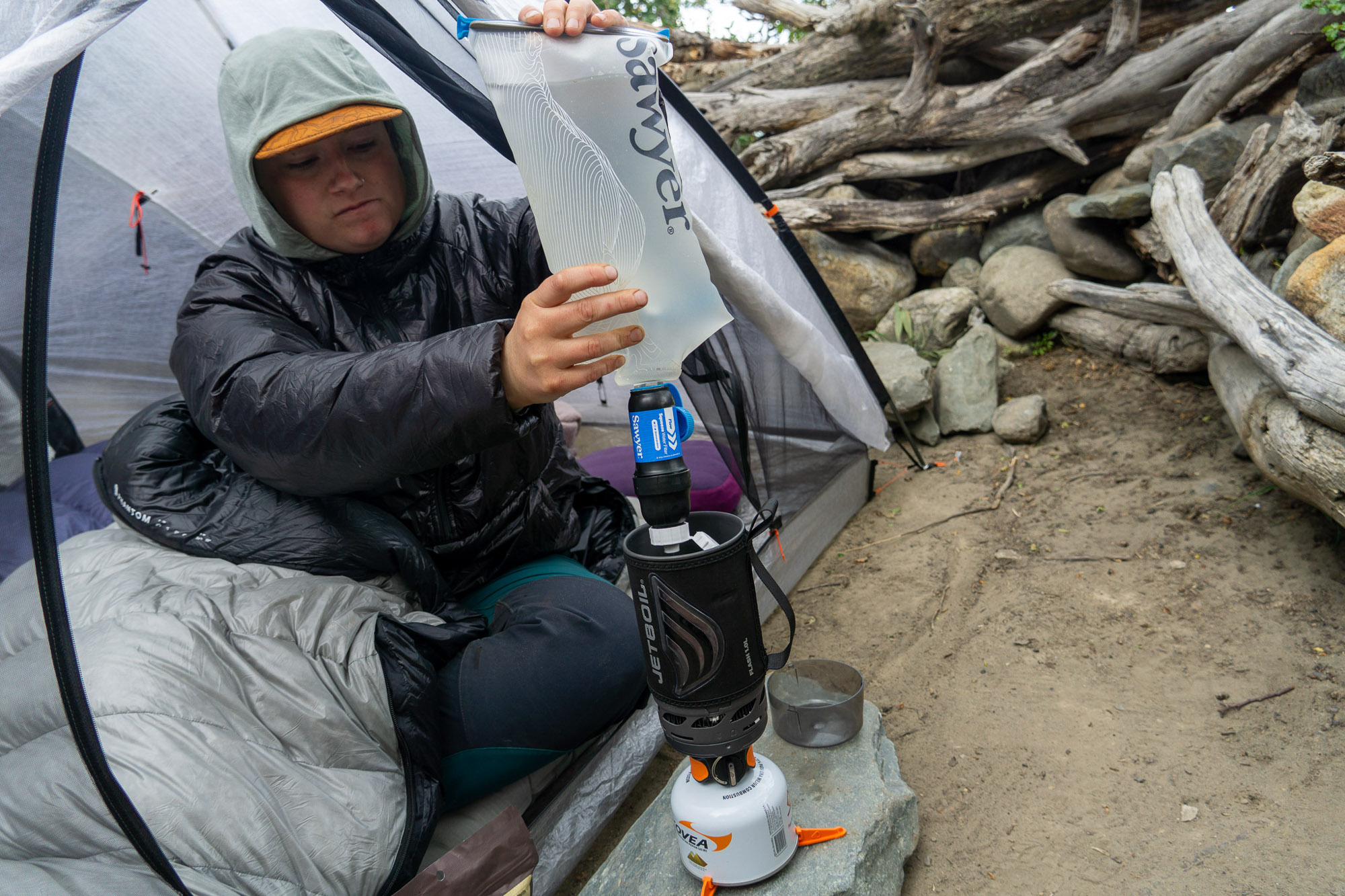 a gearjunkie tester squeezing water from the sawyer squeeze filter into a jetboil stove in patagonia