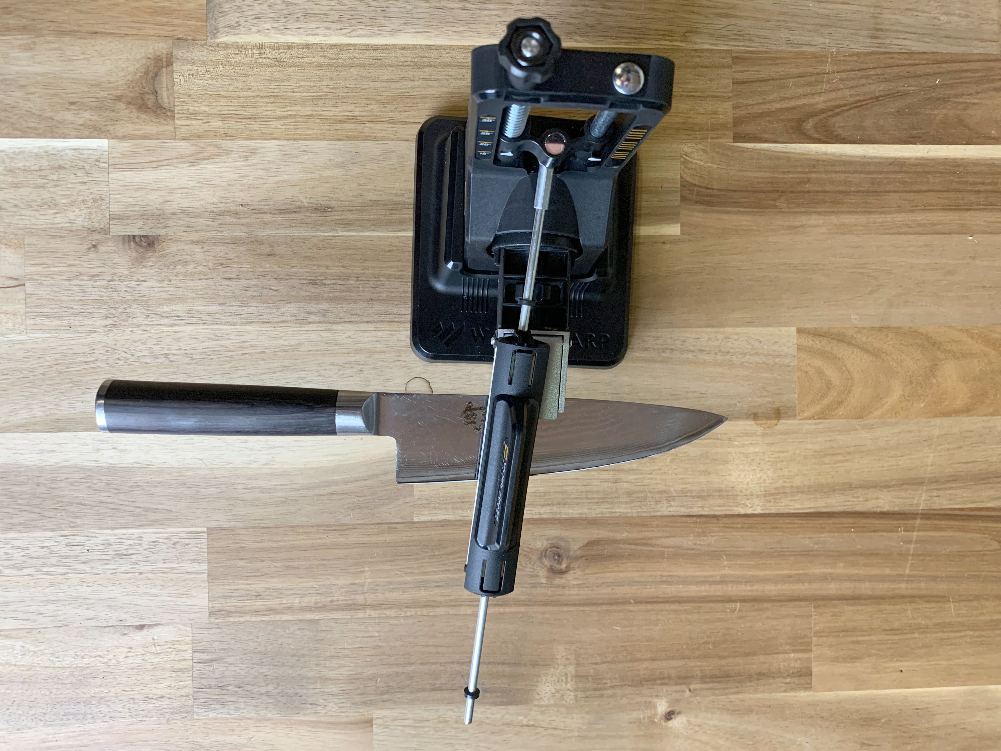 a top-down image of a chef knife in a guided-angle manual style sharpener