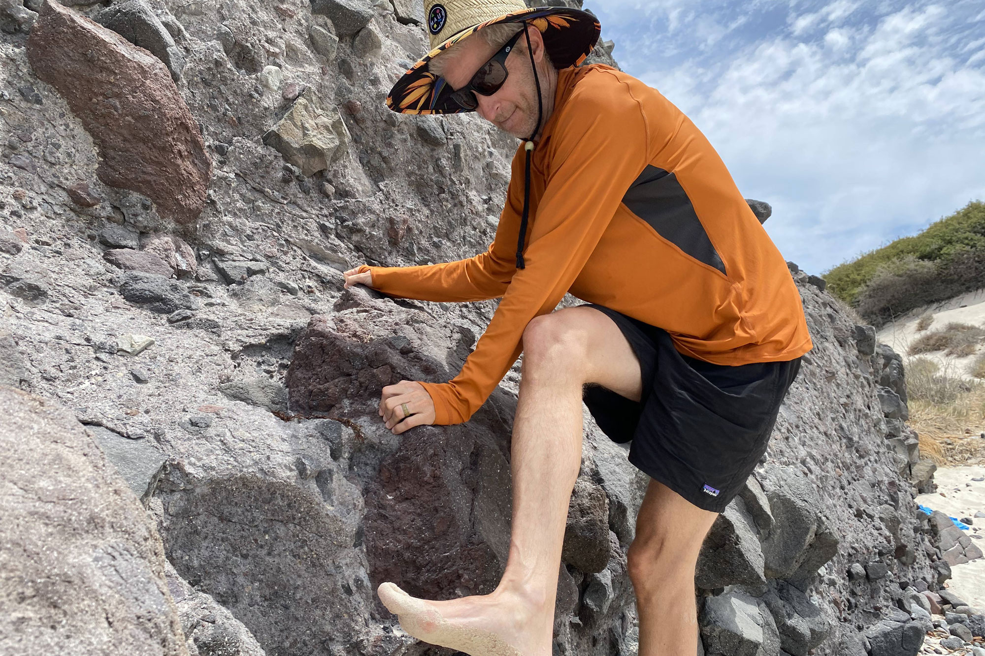 Man with a hat and Black Diamond Alpenglow Pro Hoody climbing