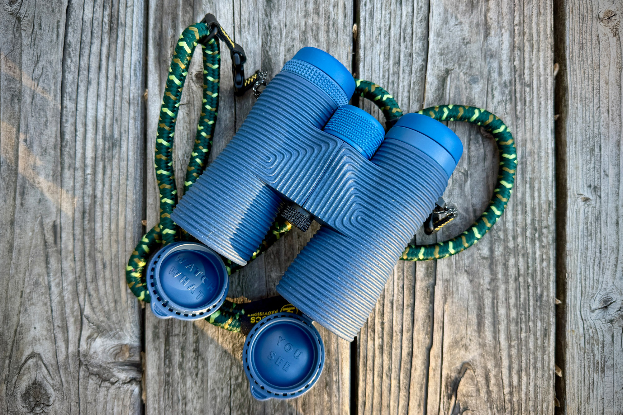 NOCS Provisions Field Issue 42 binoculars resting on wood with strap and lens caps attached