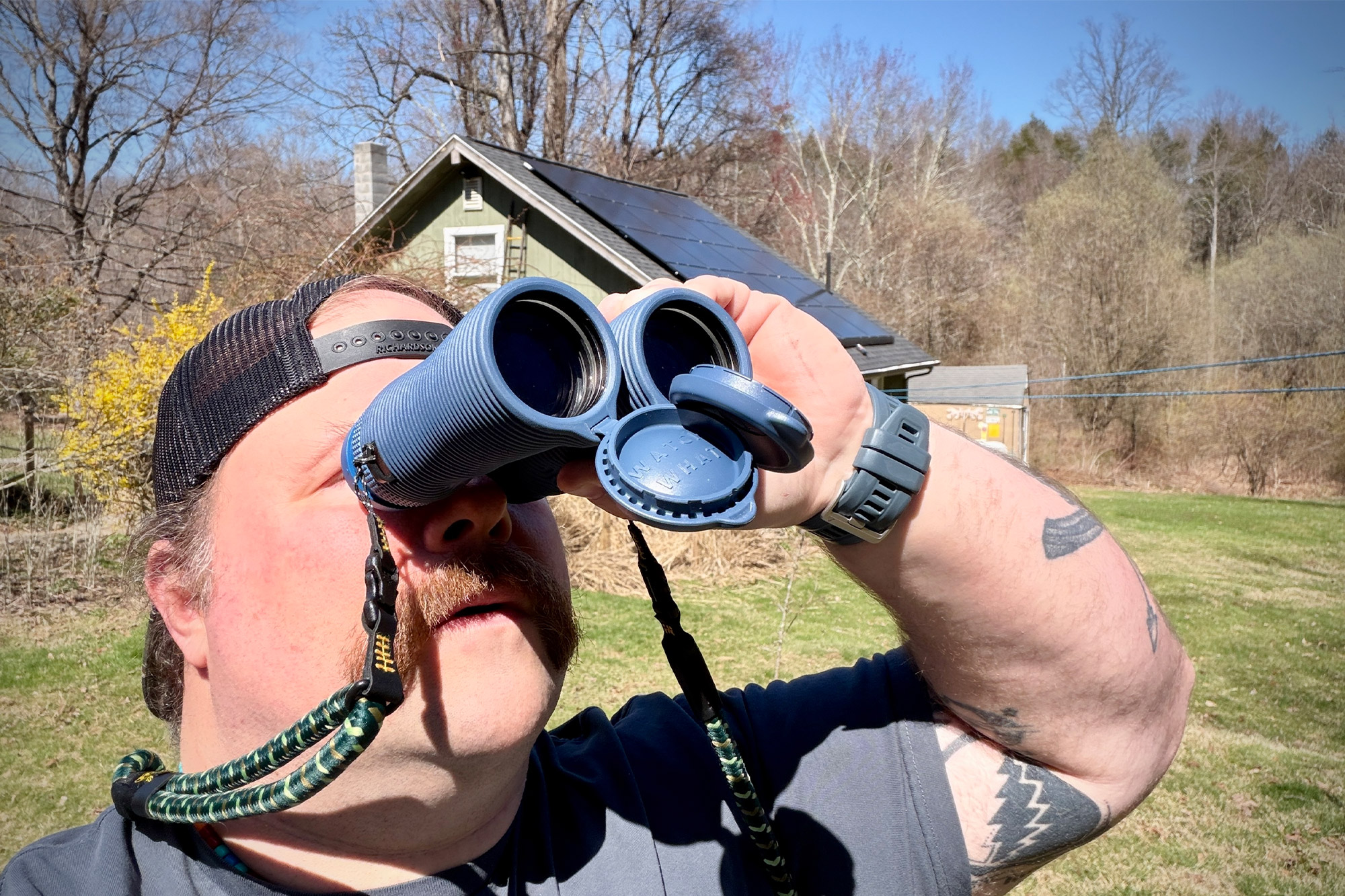 Field Issue binoculars used for viewing outdoors in a yard with house in background