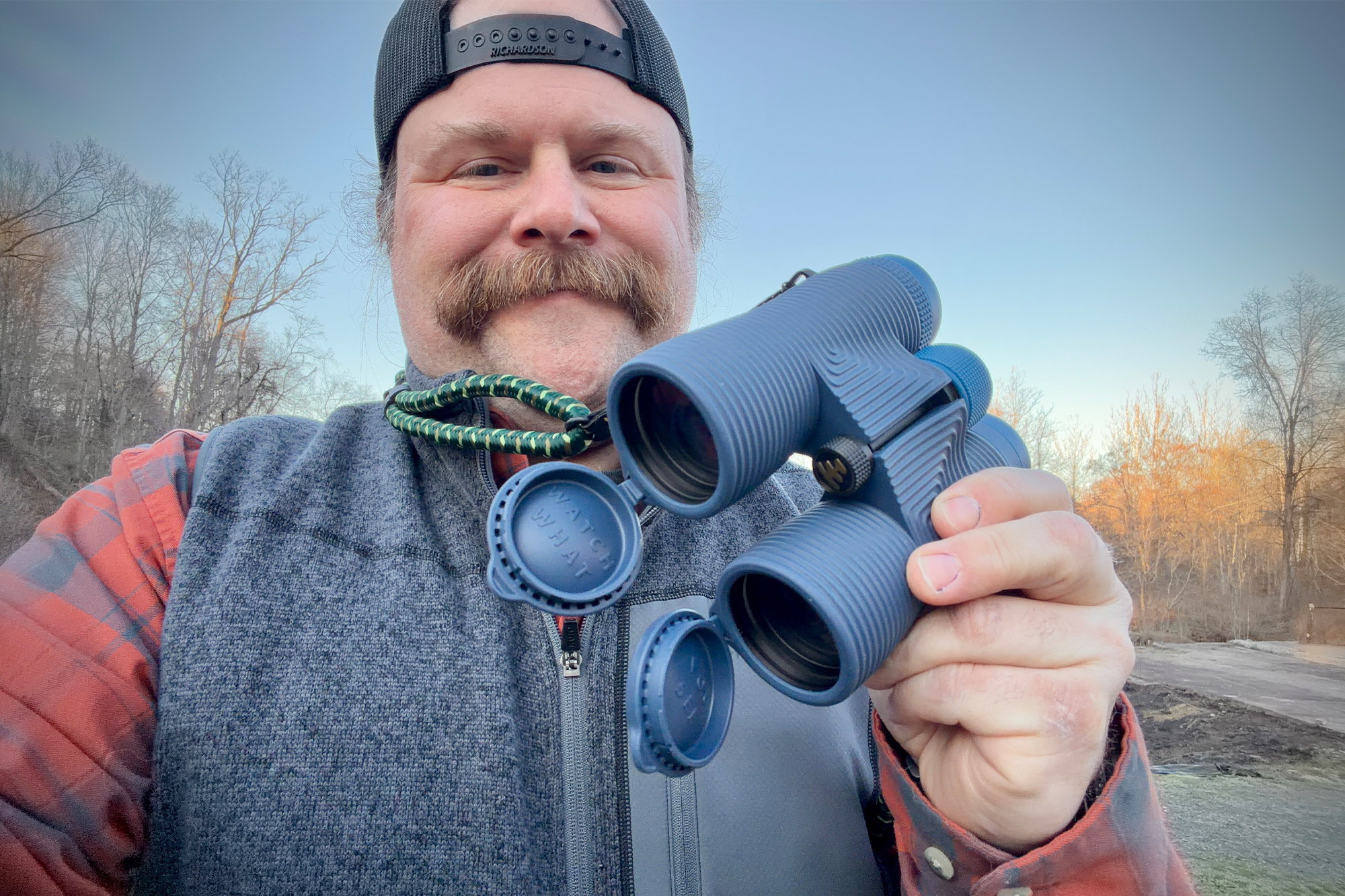 NOCS Provisions binoculars held in hand outdoors with lens caps open