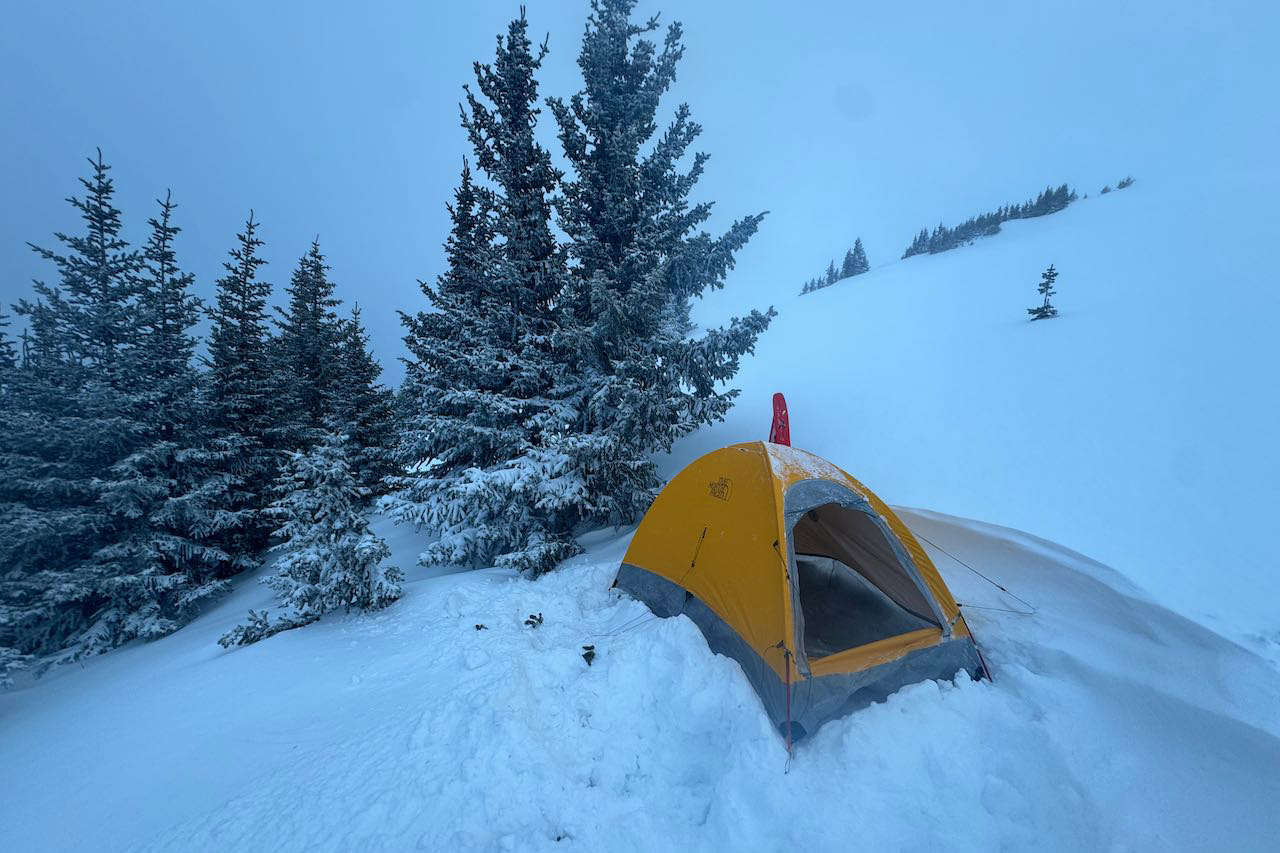 Assault 2 AMK tent pitched in snowy storm conditions near trees