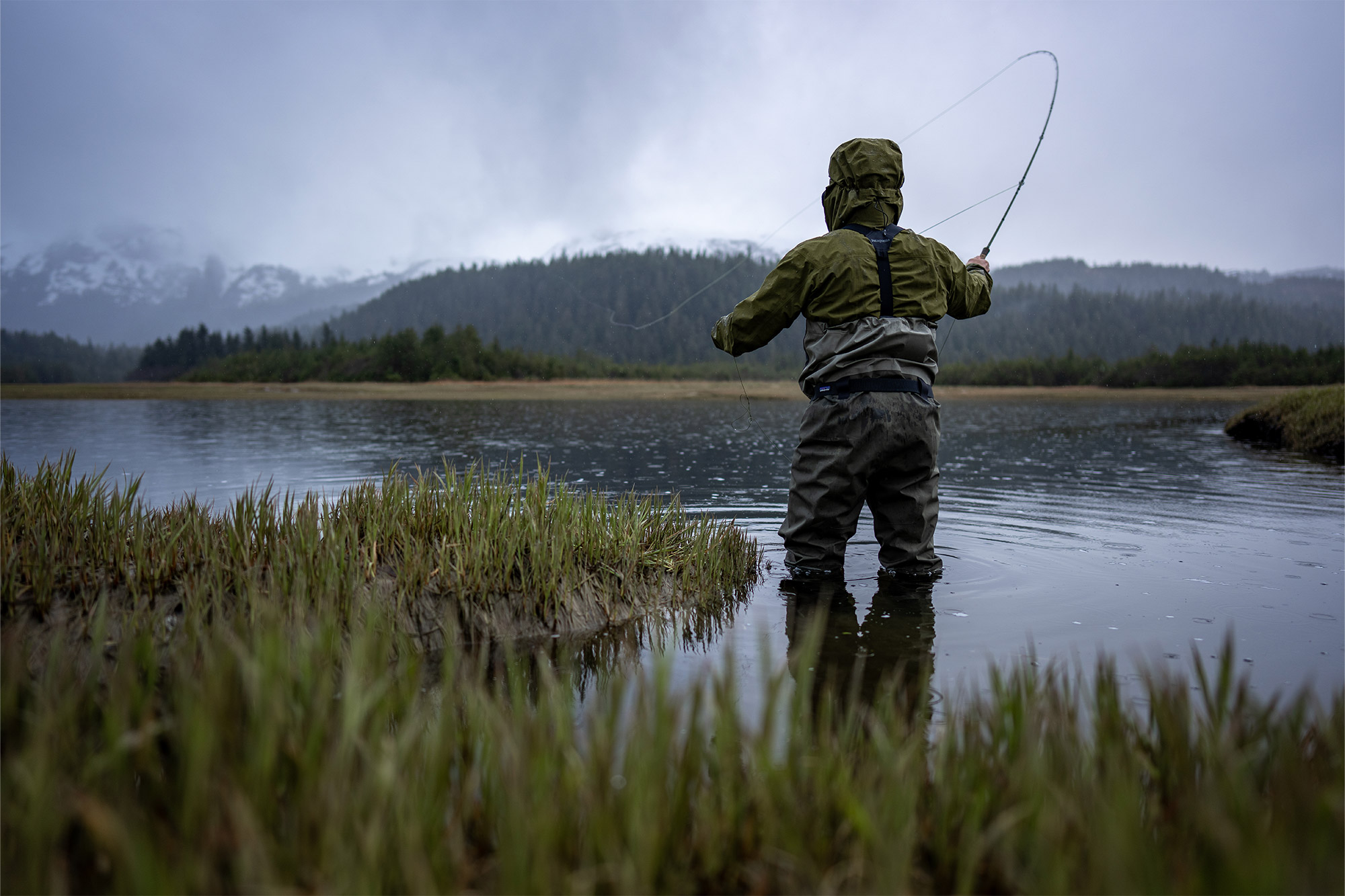 Patagonia Swiftcurrent Traverse Waders in the water from behind while casting a fishing line