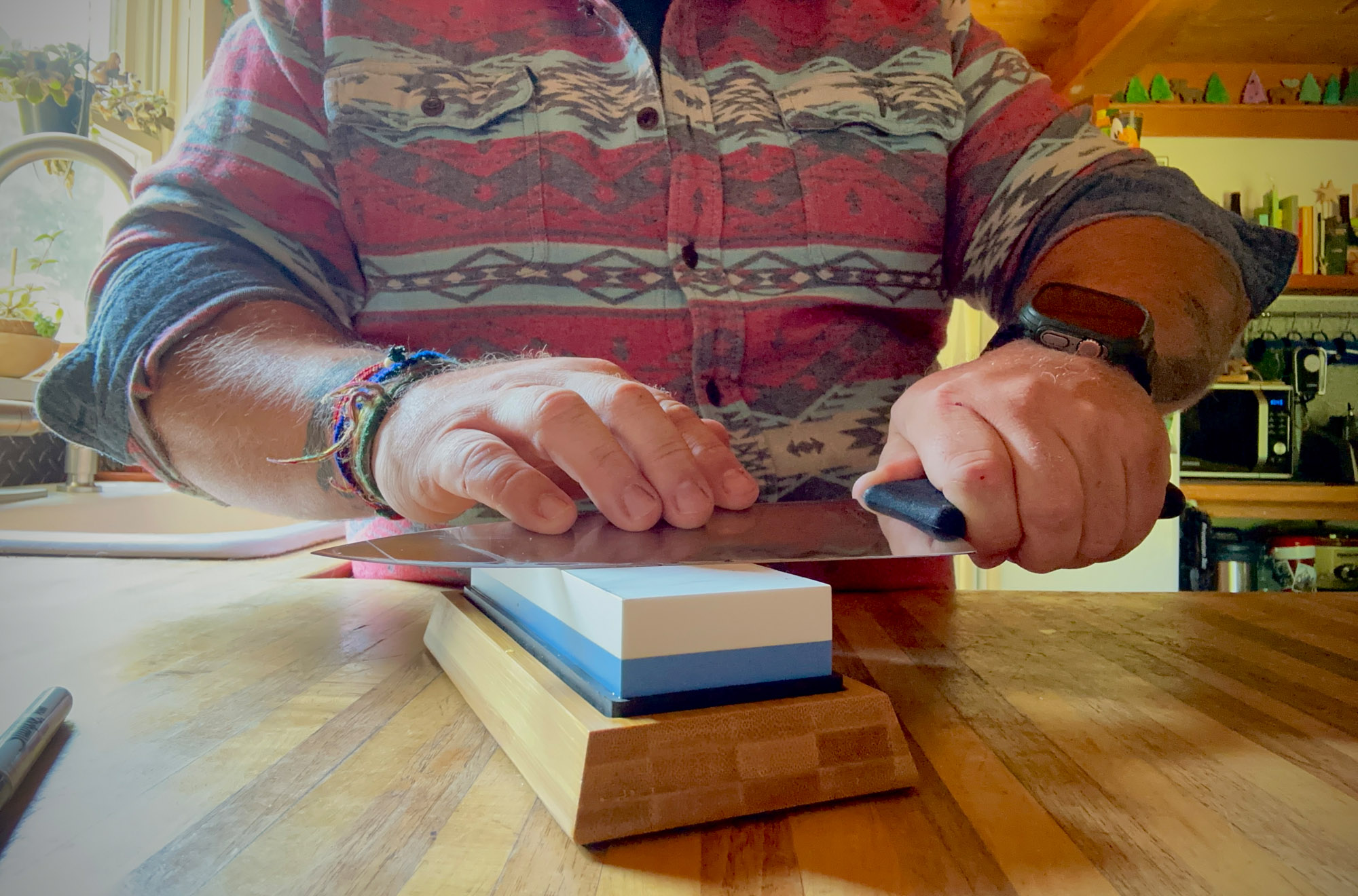 one of the authors passes a kitchen knife across the sharp pebble whetstone in a kitchen
