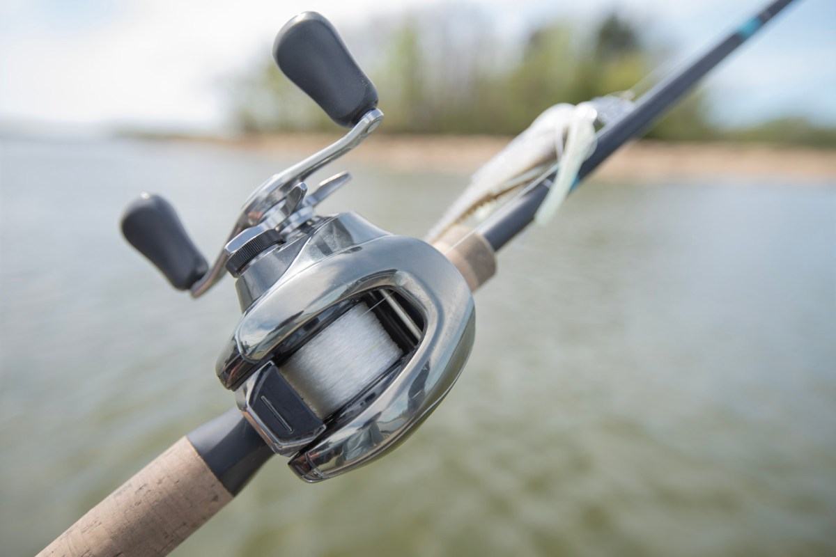 The Shimano Antares B spinning reel on a rod in front of a lake.