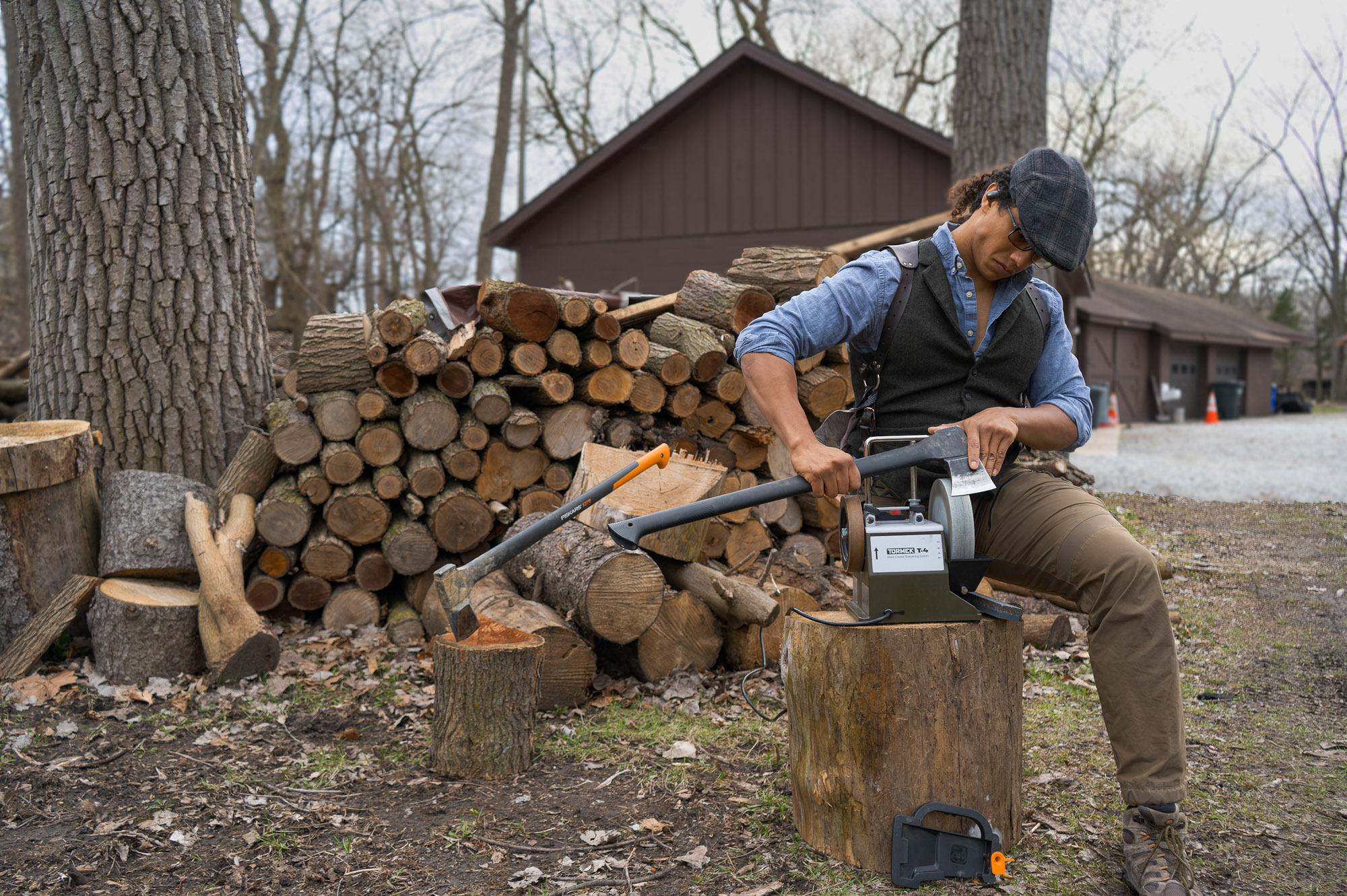 the author sharpening a splitting axe in a wood yard with a tormek electric sharpener