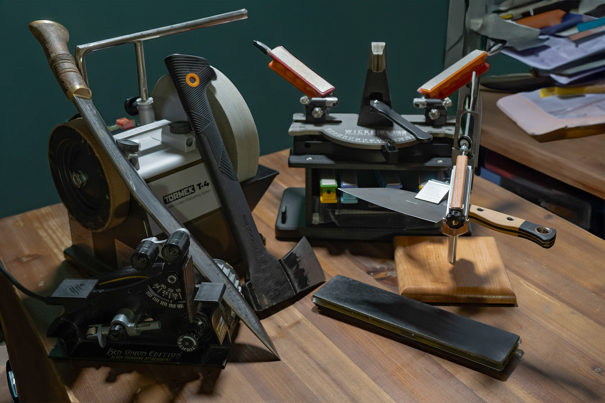 a selection of different knife sharpeners on a desk, along with different blade styles that might be sharpened on them