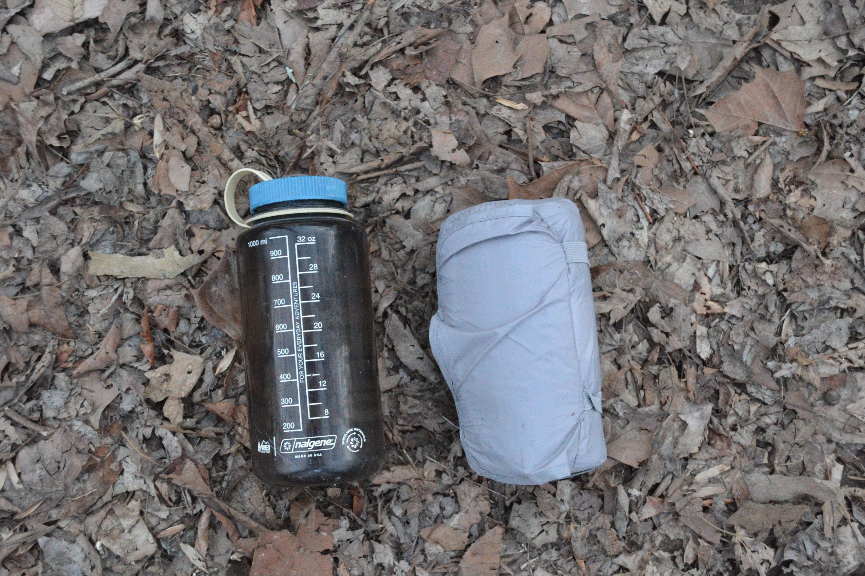 gray sleeping pad on leaves in package next to nalgene