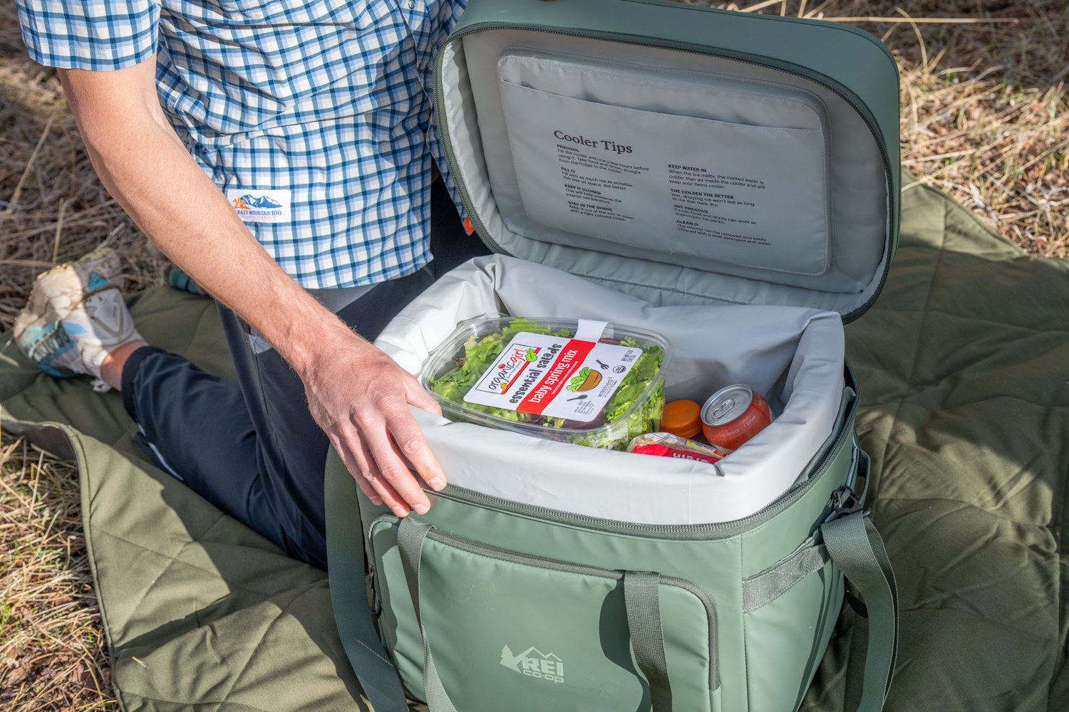 Close up of the inside lid of the REI cooler showing printed "Cooler Tips" and a slim zippered mesh pocket.