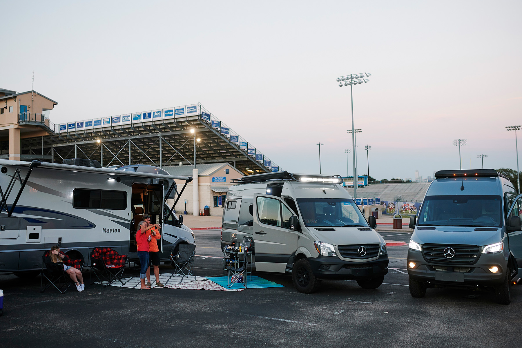 two vans and an rv parked at a sporting event