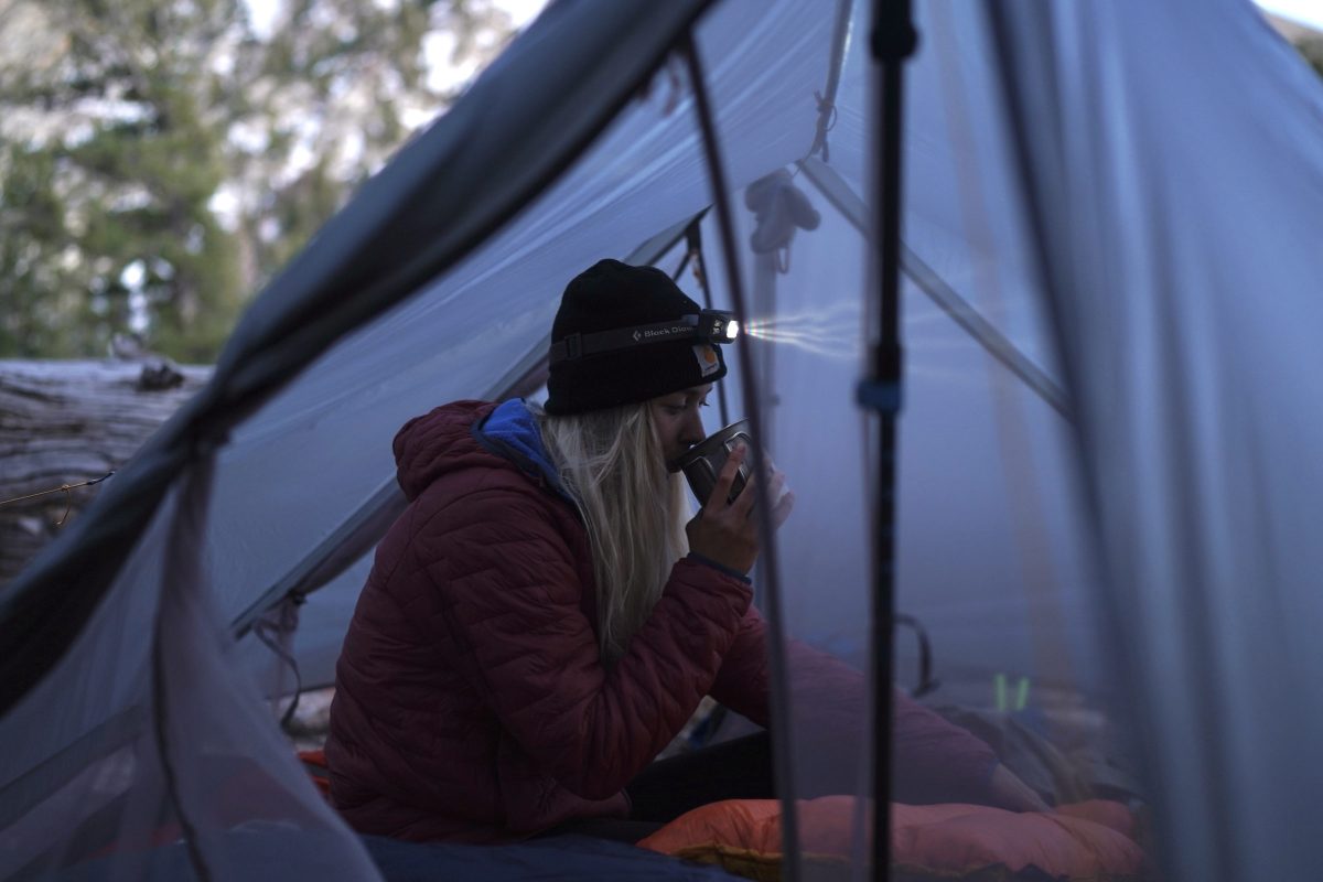 a gearjunkie tester sits inside a gossamer gear the two tent with a headlamp on